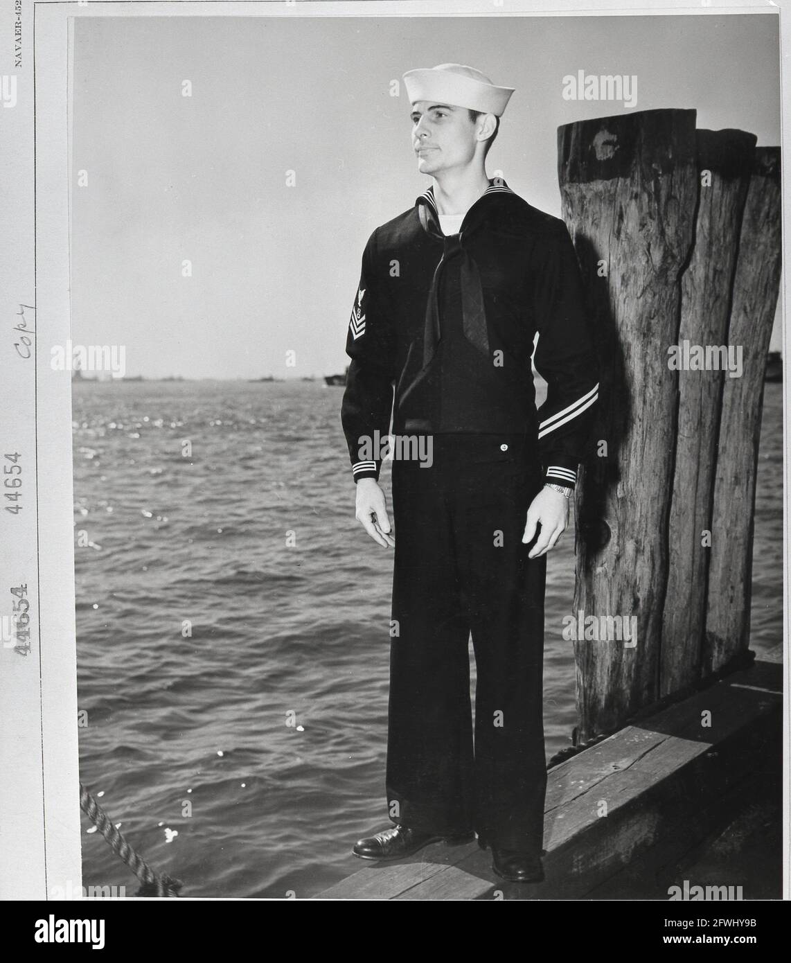 USA Weltkrieg 2. Weltkrieg 1940er Jahre US Navy Seemann Uniform Fashion Sailor posiert auf einem Dock, um seine Arbeitskleidung zu zeigen Stockfoto