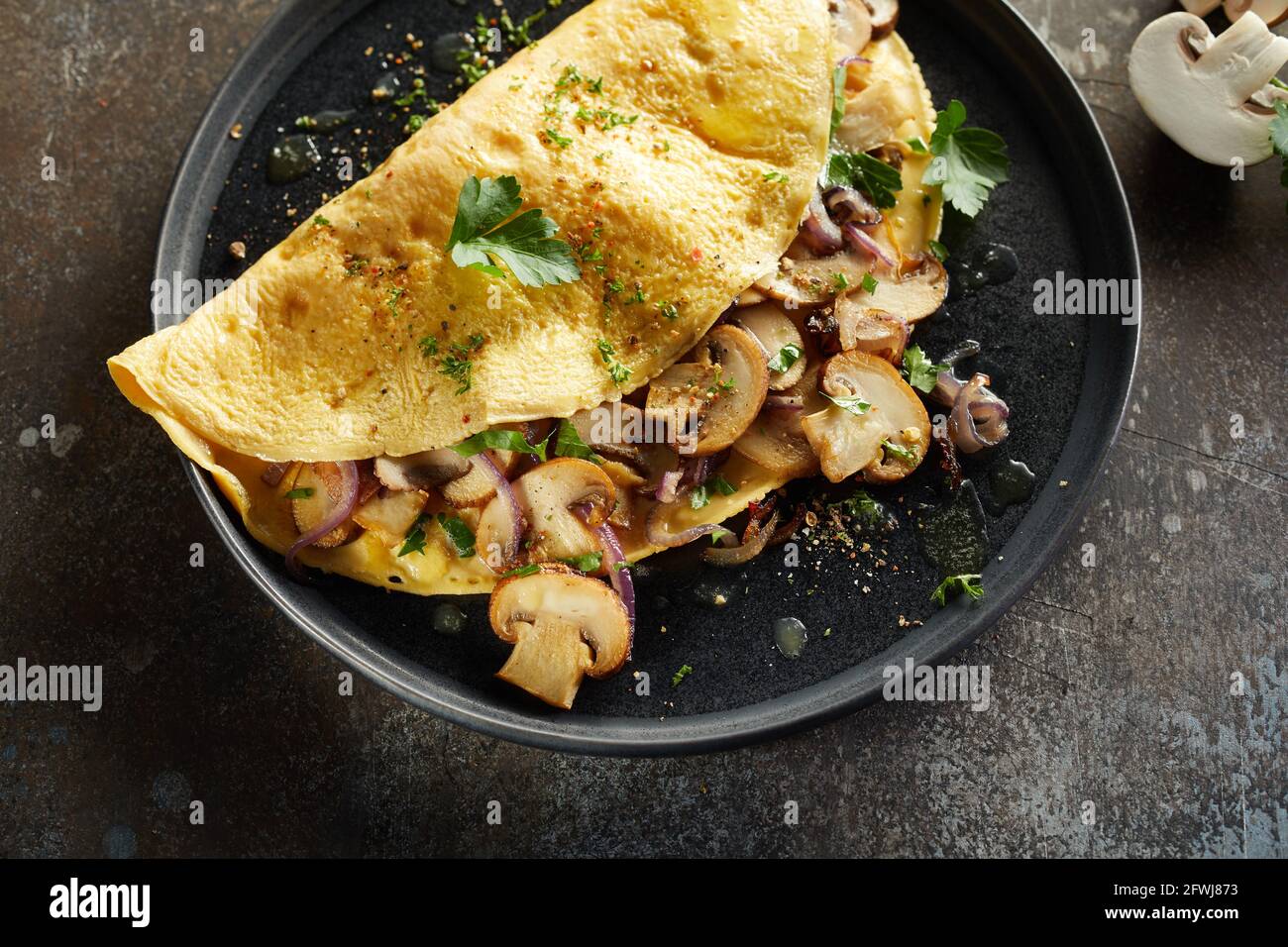 Von oben appetitliches Omelett mit Pilzen und Kräutern bestreut Mit Gewürzen auf dem Teller auf dem Tisch serviert Stockfoto