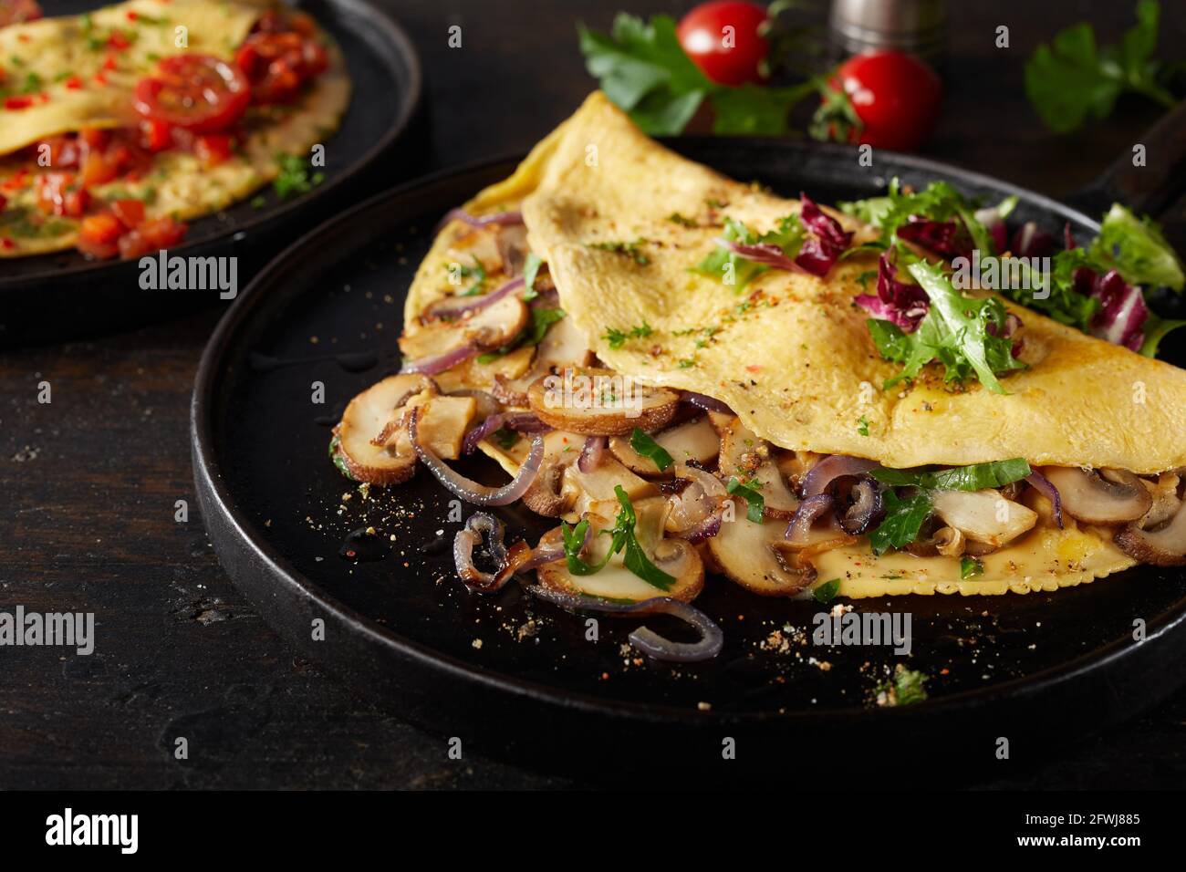 Appetitliches Omelett mit Pilzen und Salat in einem hohen Winkel serviert Auf dunklem Tisch zum Mittagessen Stockfoto