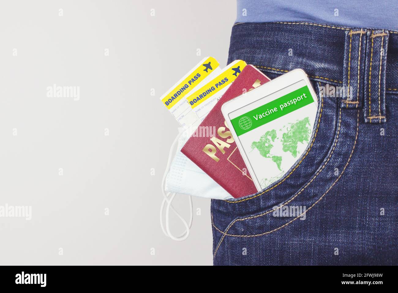 Smartphone-Bildschirm mit gültigem digitalen Impfpass für COVID-19, Reisepass, Bordkarte und Taschenmaske in einer Jeans-Tasche. Reisekonzept, Stockfoto