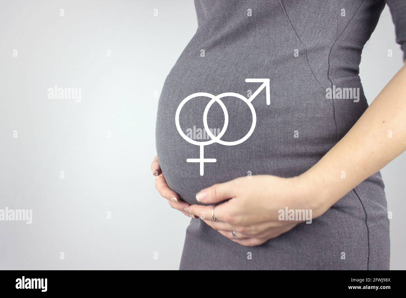 Mittelteil der Schwangeren Frau berührt Bauch mit Hologramm männlichen und weiblichen Geschlechts-Symbol von Grey Background. Vorbereitung und Erwartung Konzept. Schließen Stockfoto