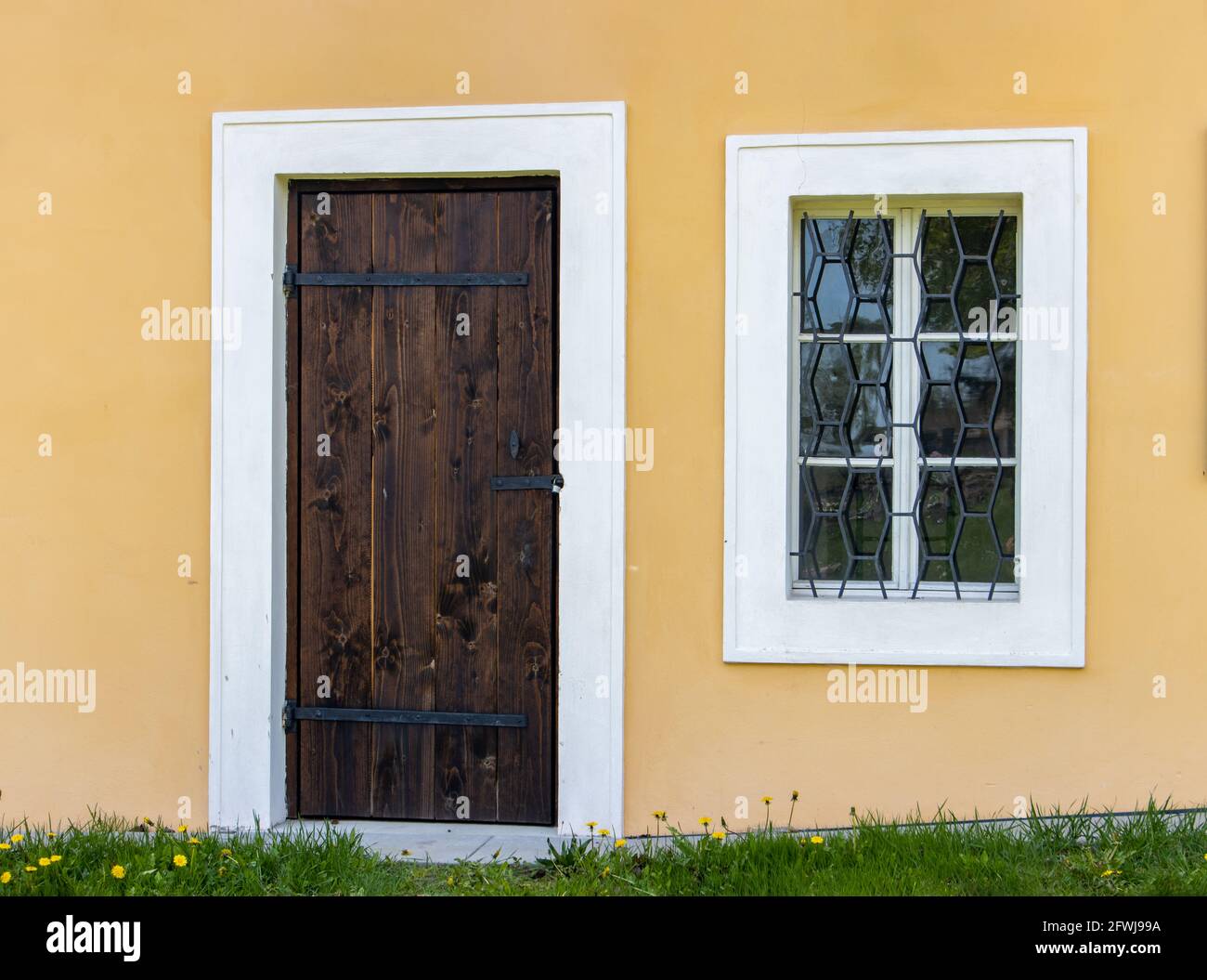 Tür mit versperrtem Fenster eines historischen Gebäudes. Außenansicht einer Leichenhalle auf einem Friedhof. Stockfoto