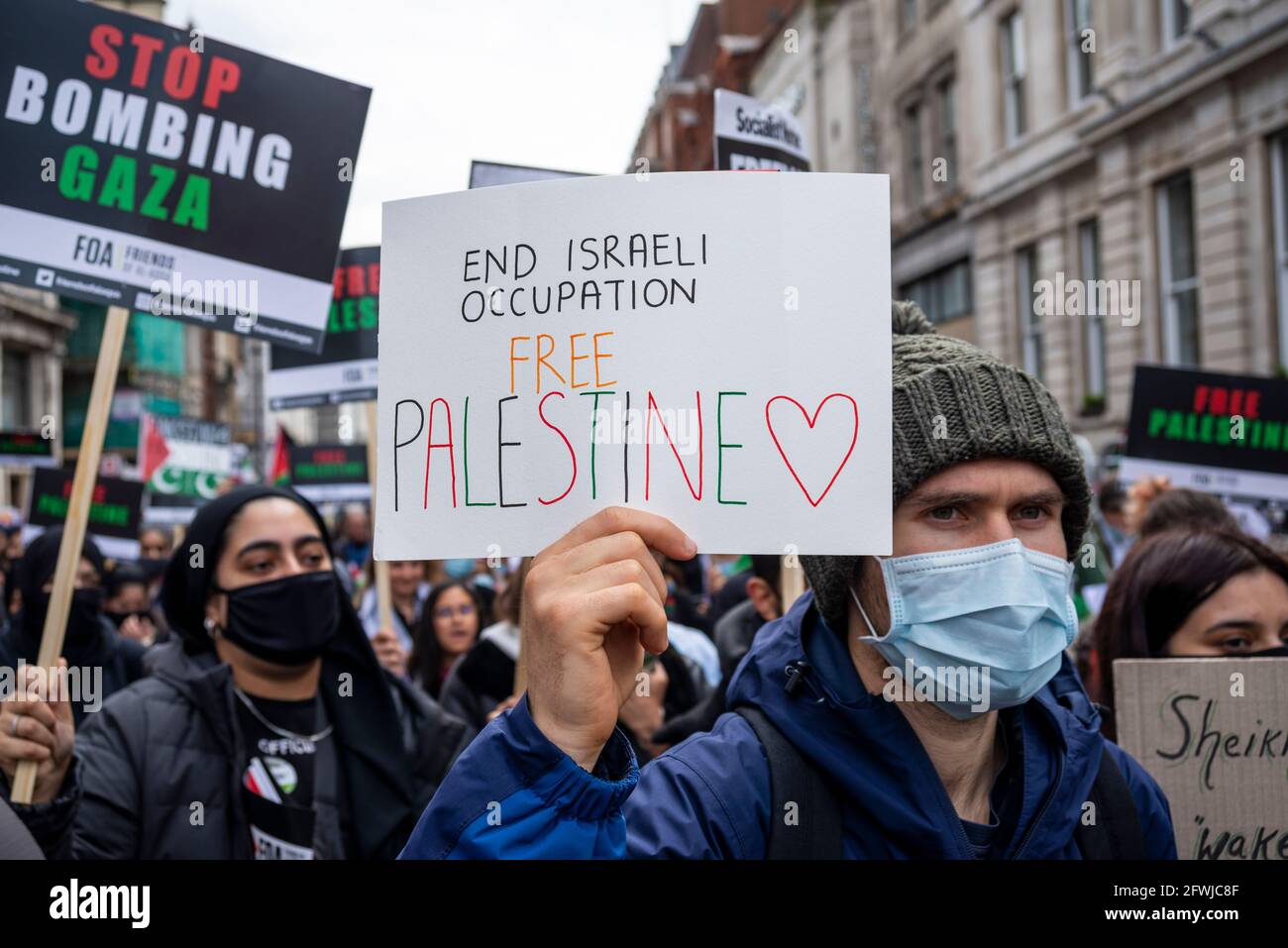Protestierende bei der Nationalen Demonstration für Palästina, Freie Palästina, in London, Großbritannien. Männlich trägt Gesichtsmaske. Plakat. Beendet die israelische Besatzung. Stockfoto