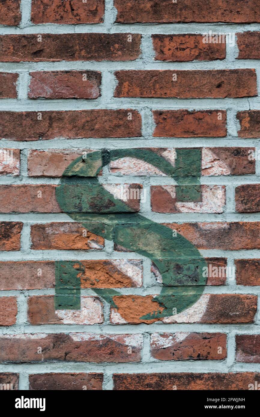 Ein grüner Buchstabe s auf einer roten Ziegelwand gemalt Stockfoto
