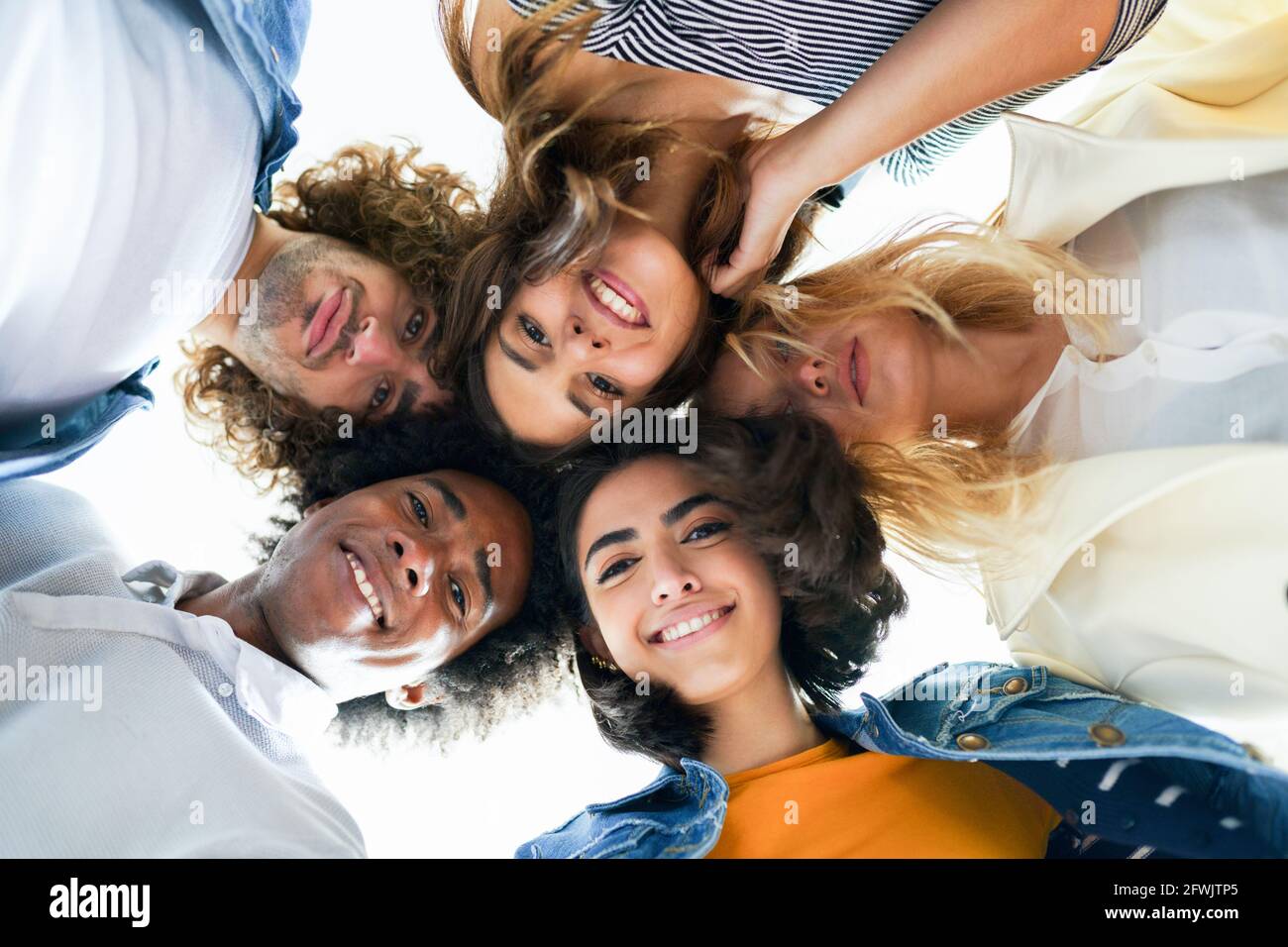 Multiethnische Gruppe von Freunden mit ihren Köpfen zusammen in einem Kreis. Stockfoto