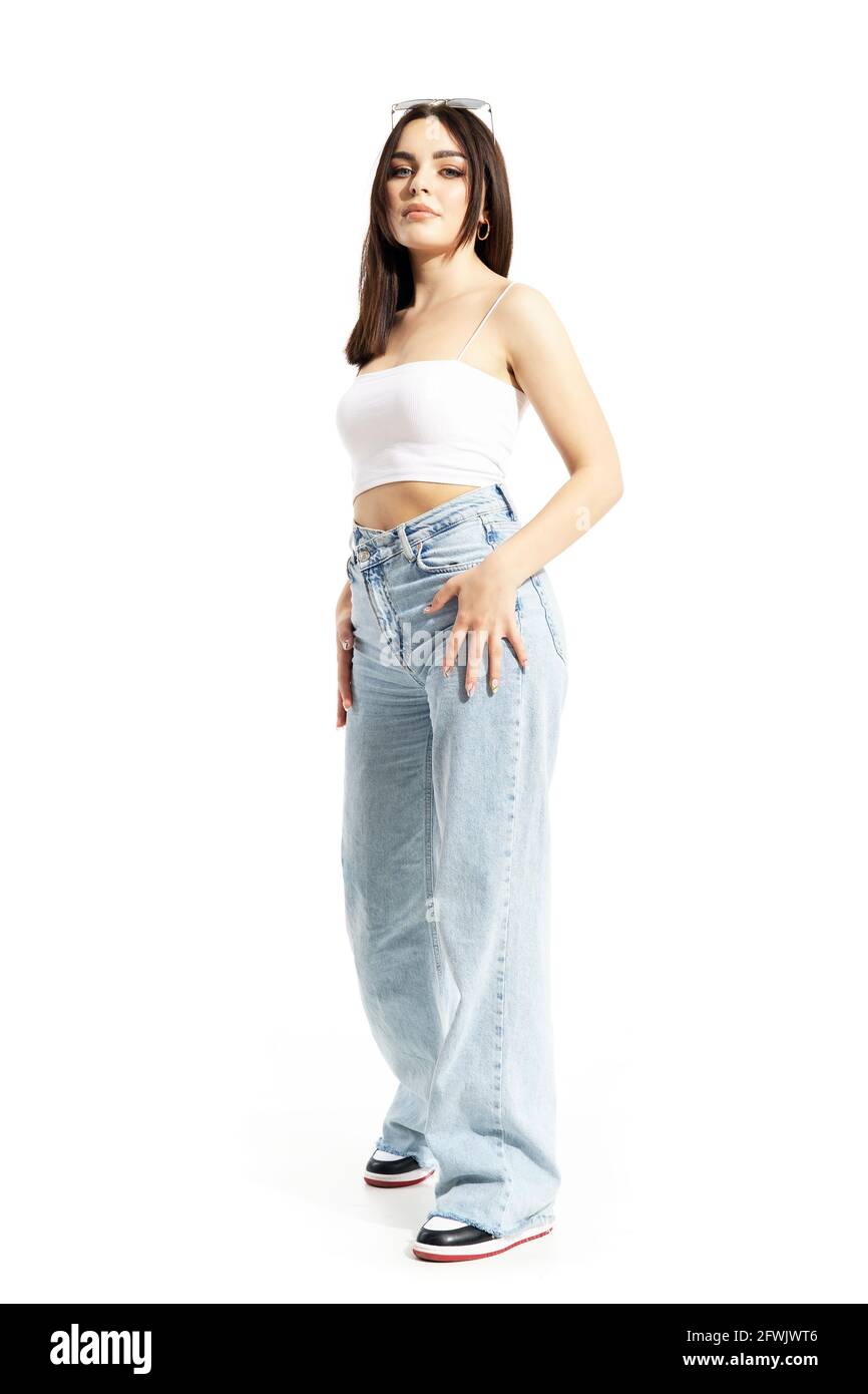 Selbstbewusste trendige schöne Frau posiert in Jeans und Sneakers. Ganzkörperlänge isoliert auf weißem Hintergrund Stockfoto