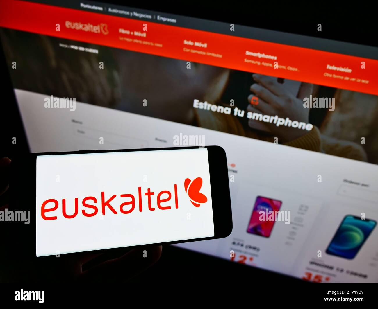 Person, die Mobiltelefon mit dem Logo des spanischen Telekommunikationsanbieters Euskaltel S.A. auf dem Bildschirm vor der Webseite hält. Konzentrieren Sie sich auf die Telefonanzeige. Stockfoto