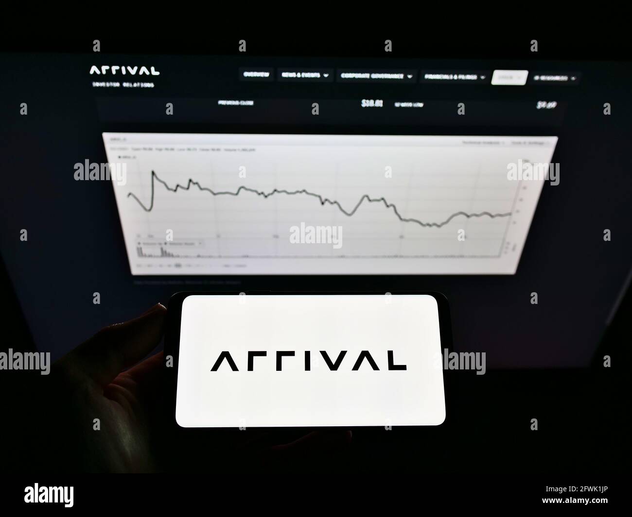 Person, die Mobiltelefon mit Logo des Elektrofahrzeugherstellers Arrival Ltd. Auf dem Bildschirm vor der Website mit Diagramm hält. Konzentrieren Sie sich auf die Telefonanzeige. Stockfoto