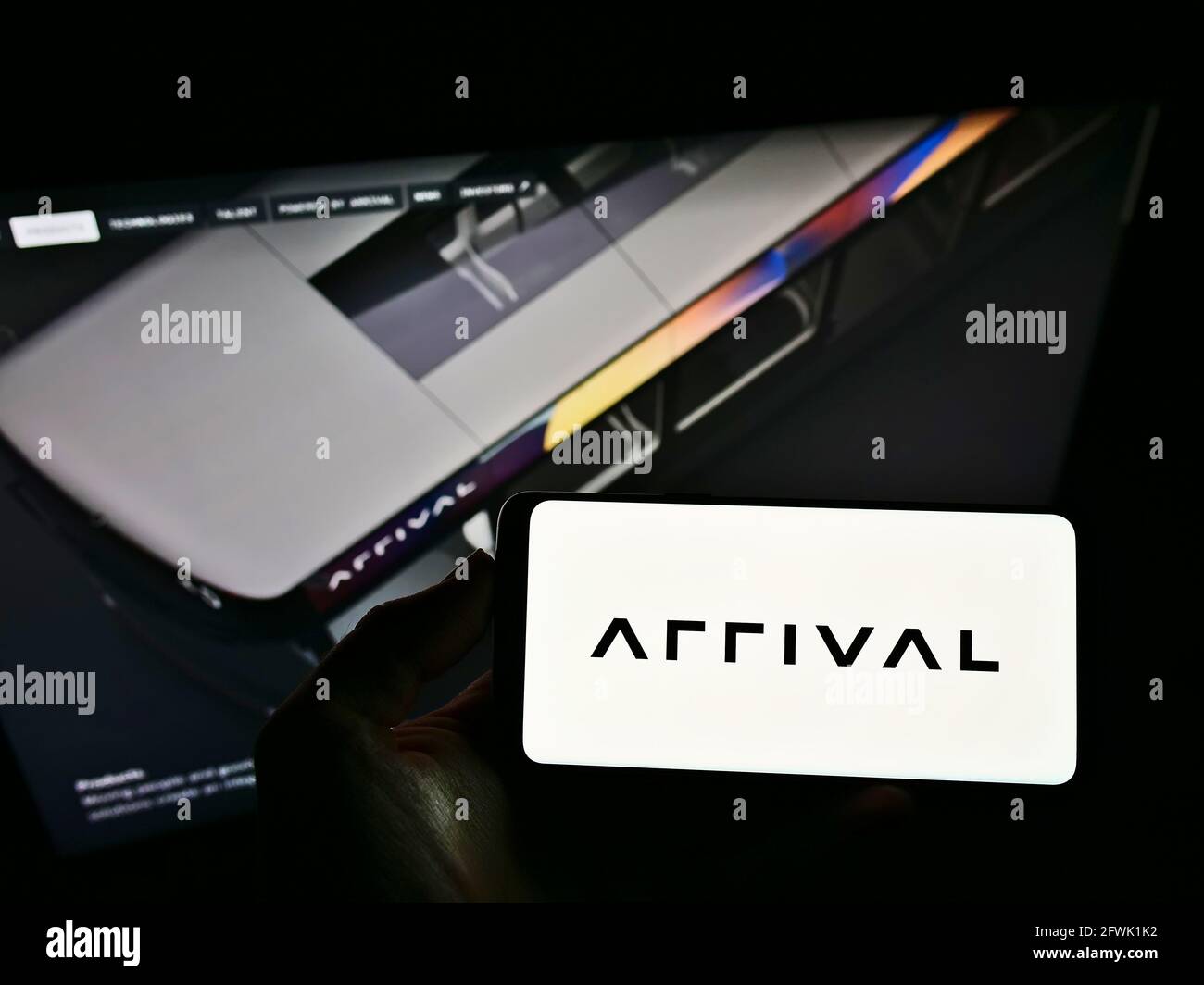 Person, die ein Mobiltelefon mit dem Logo des Elektrofahrzeugherstellers Arrival Ltd. Auf dem Bildschirm vor der Unternehmenswebseite hält. Konzentrieren Sie sich auf die Telefonanzeige. Stockfoto