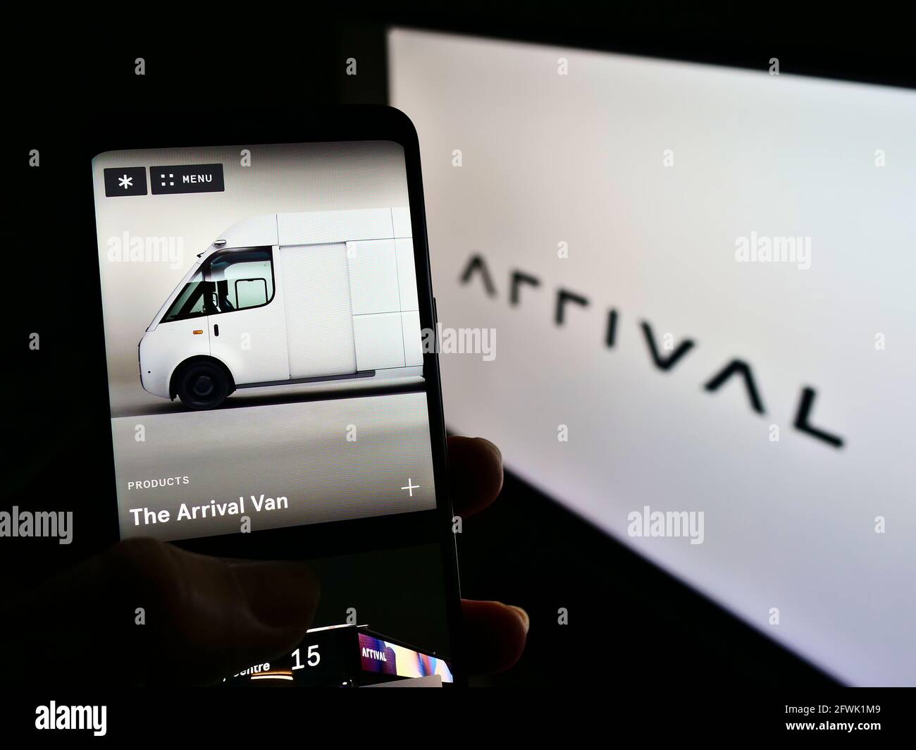 Person, die Mobiltelefon mit der Webseite des Elektrofahrzeugherstellers Arrival Ltd auf dem Bildschirm vor dem Logo hält. Konzentrieren Sie sich auf die Mitte des Telefondisplays. Stockfoto