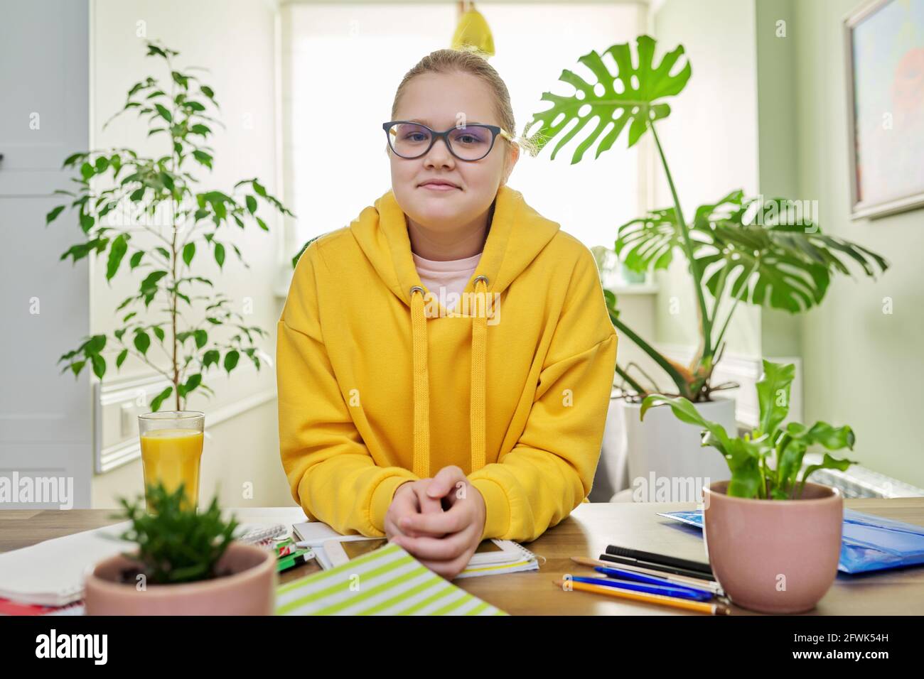 Porträt des Mädchens 12, 13 Jahre alt in gelbem Sweatshirt mit Brille, die auf die Kamera schaut Stockfoto