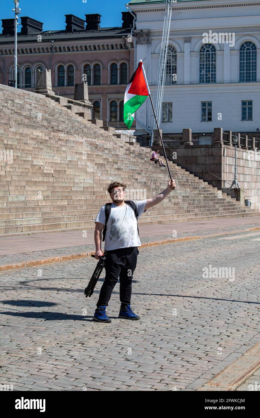 Männlicher Protestler, der die Flagge Palästinas auf dem Senatsplatz schwenkte, bevor er im Namen Palästinas in Helsinki, Finnland, einen Solidaritäts-Marsch durchmarschierte Stockfoto