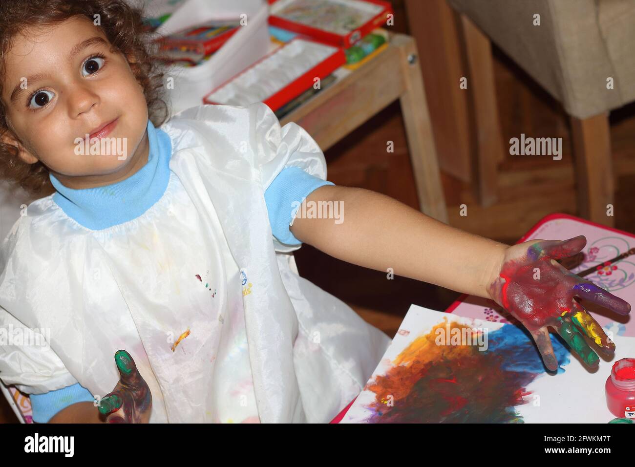 Kleine Malerin mischt neugierig Farben, aber mit ihren Händen statt Palette Stockfoto