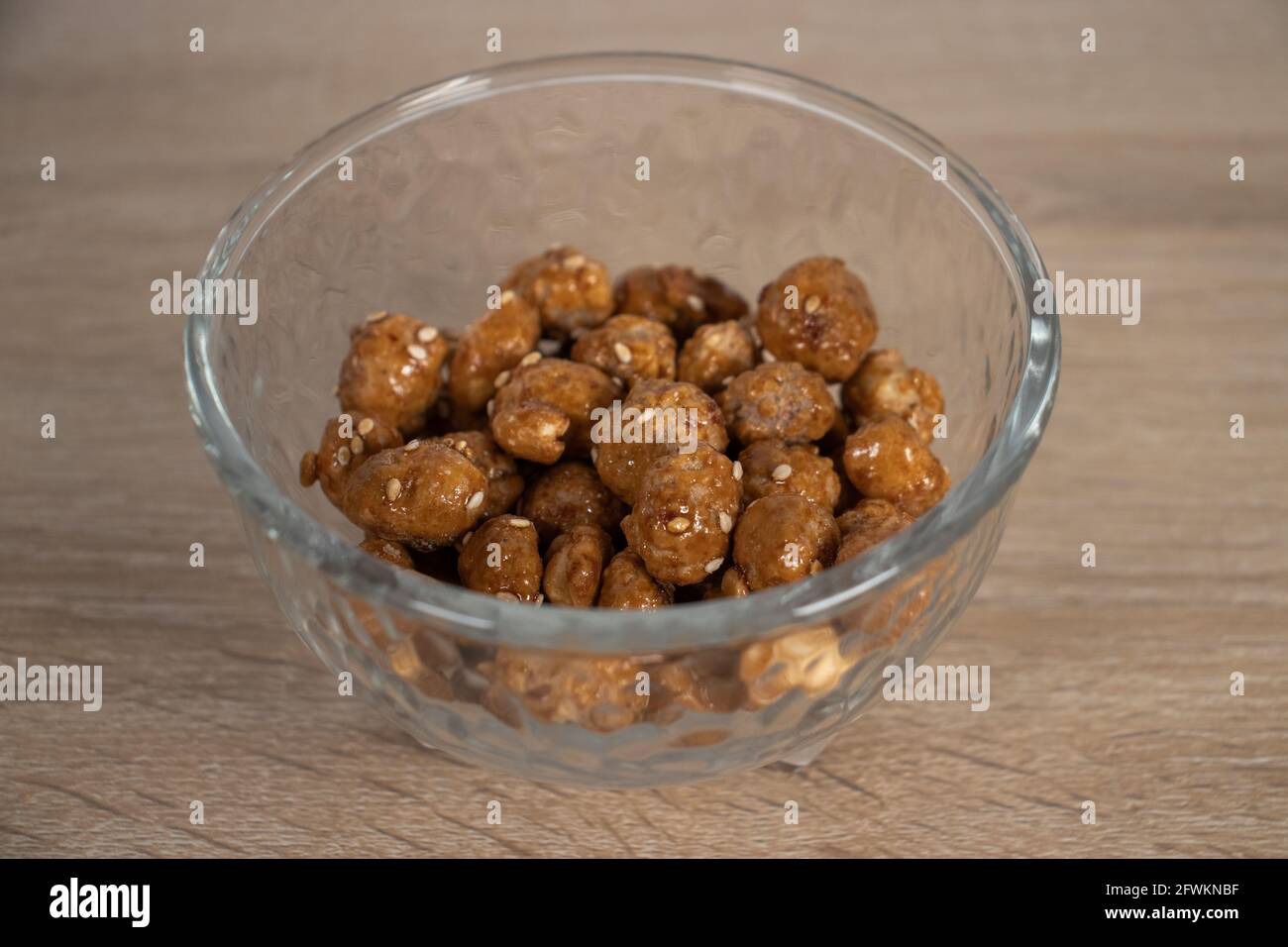 Karamellisierte Erdnüsse mit Sesam auf Glasschale. Garapiñados. Garrapiñados. Mit Zucker beschichtete Erdnüsse. Stockfoto