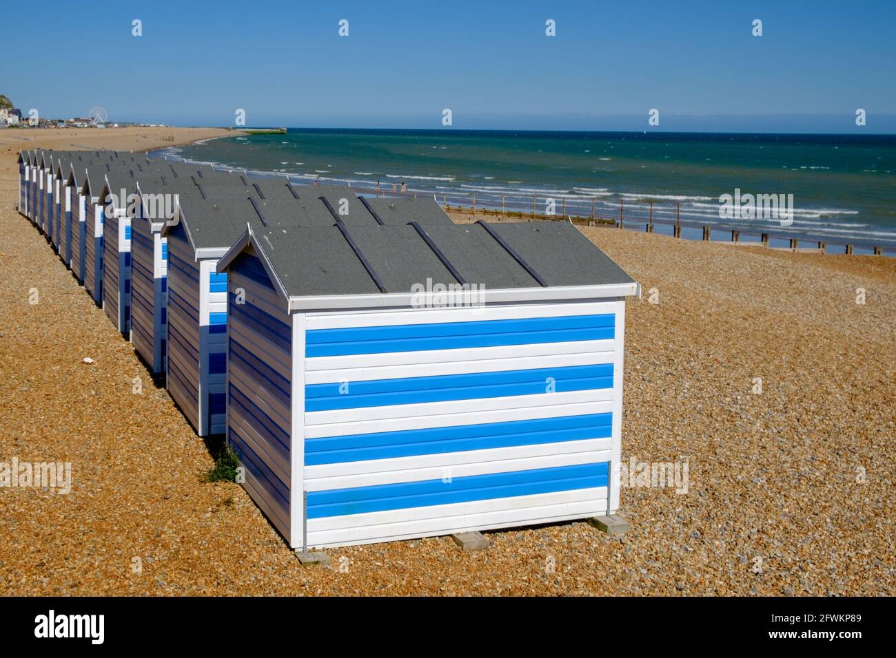 Staycation Idee. Reihe Blue and White Stripped Beach Huts am Hastings Beach, East Sussex, England, Großbritannien. Stockfoto