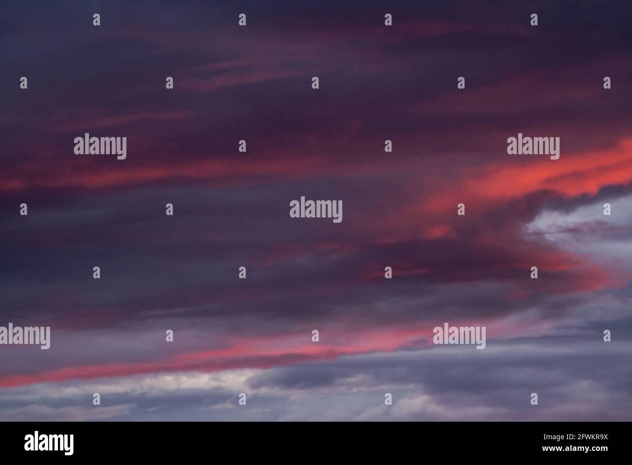 Wolken im Sonnenuntergang. Tiefgraues Blau und helle warme Farben. Stockfoto