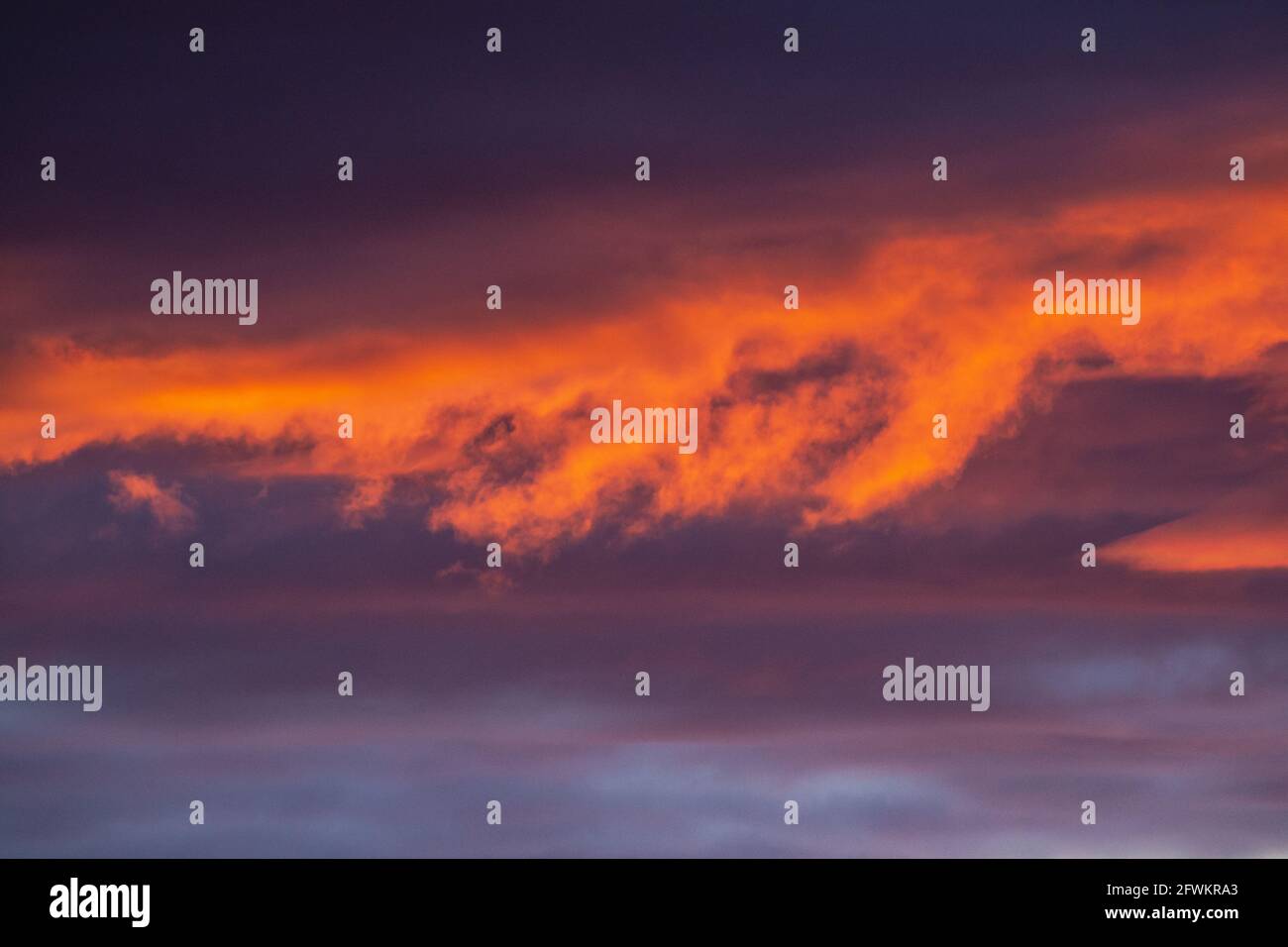 Wolken im Sonnenuntergang. Tiefgraues Blau und helle warme Farben. Stockfoto