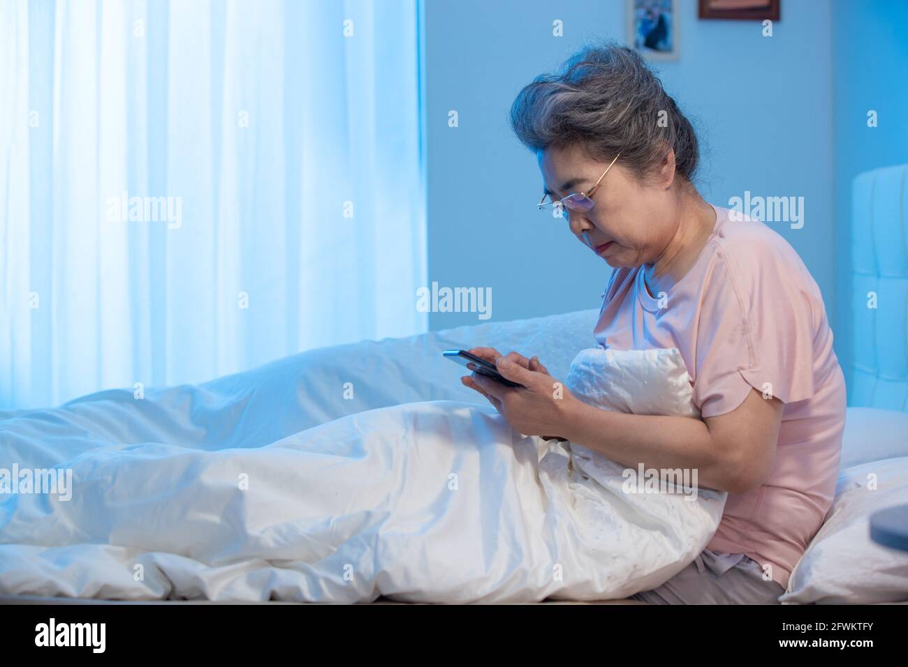 Alte Leute sitzen auf dem Bett, um ein Handy zu sehen Telefon Stockfoto