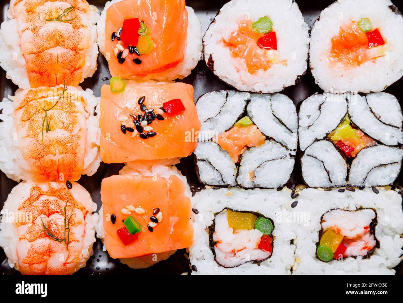 Verschiedene Sorten von verzehrfertigem Sushi aus Reis, Fisch, Nori-Algen, Schalentieren, Gemüse und Gemüse. Typisches Gericht der japanischen Küche. Stockfoto
