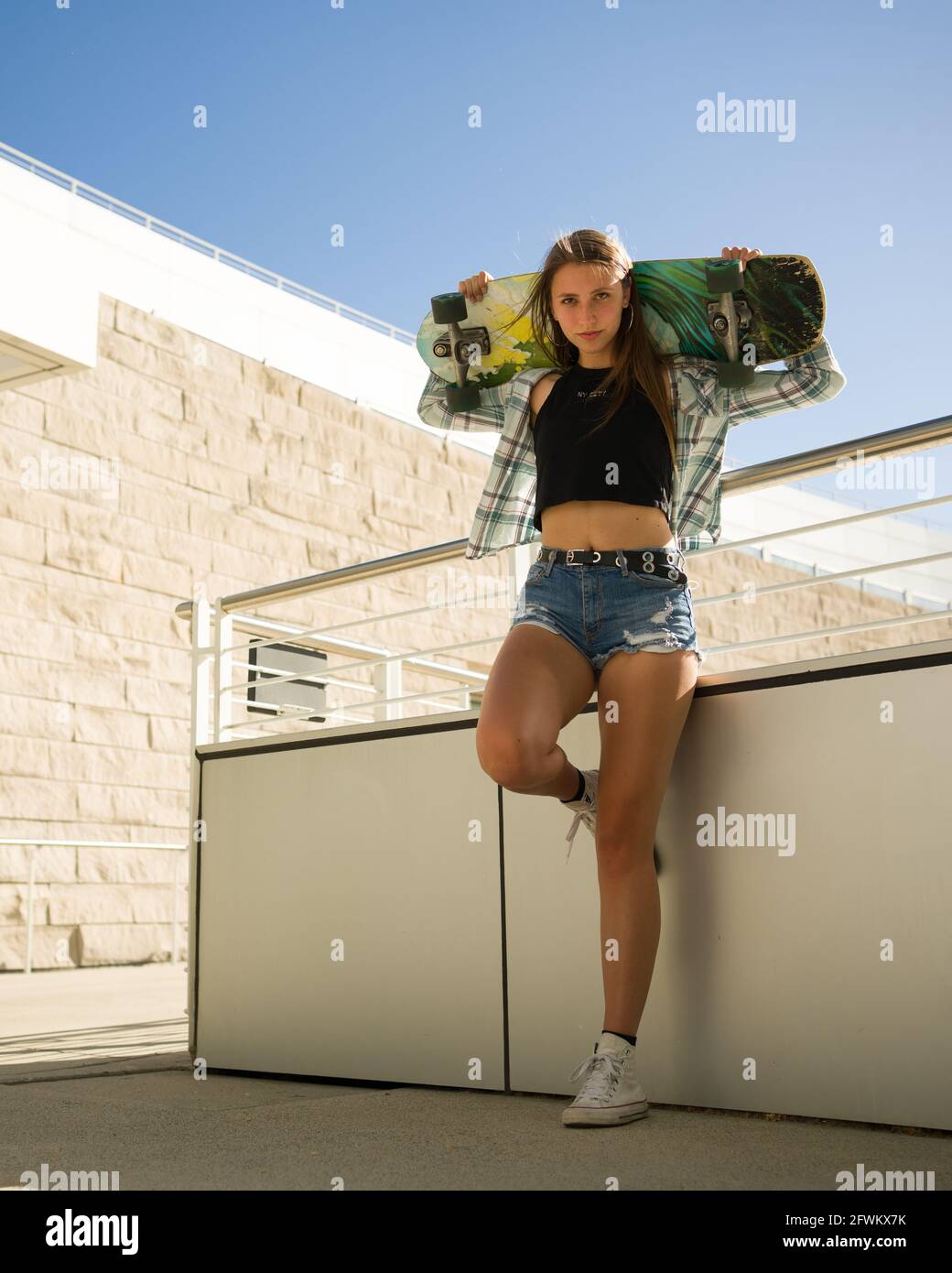 Junge Frau, die ein Skateboard in einer Innenstadtumgebung hält Stockfoto