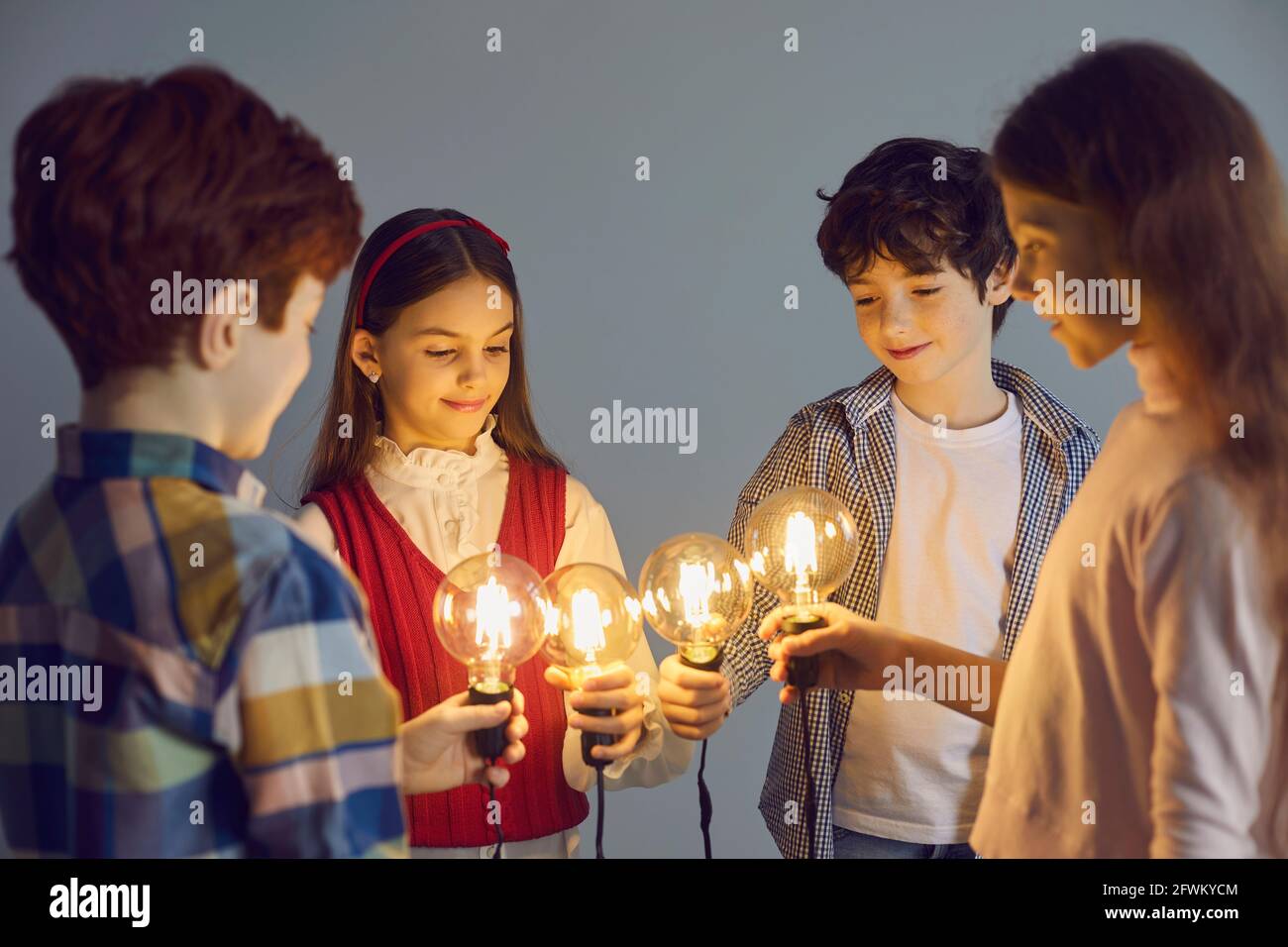 Schulkinder verbinden Idee Glühbirne zusammen stehend im Kreis studioaufnahme Stockfoto