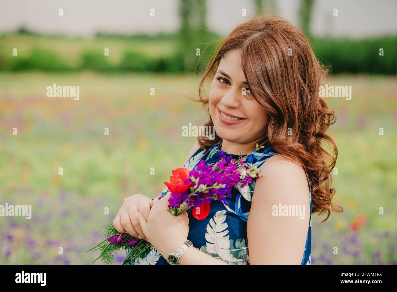 Nahaufnahme einer glücklichen und lächelnden Frau mit Lavendel Bouquet und stehen auf dem Feld voller wilder Blumen Stockfoto