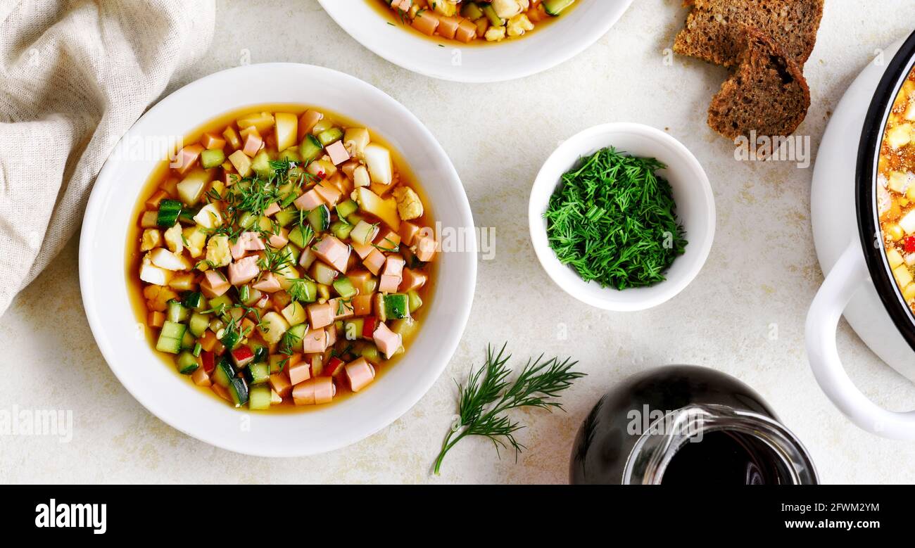 Kalte Suppe Okroschka mit Wurst, Gemüse und Kvass über hellem Stein Hintergrund. Draufsicht, flaches Lay Stockfoto