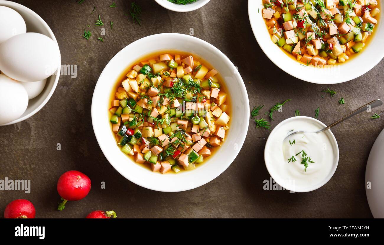 Traditionelle kalte russische Suppe Okroschka mit Wurst, Gemüse und Kvass über braunem Hintergrund. Leckeres Sommergericht zum Abendessen. Draufsicht, flacher Lay Stockfoto
