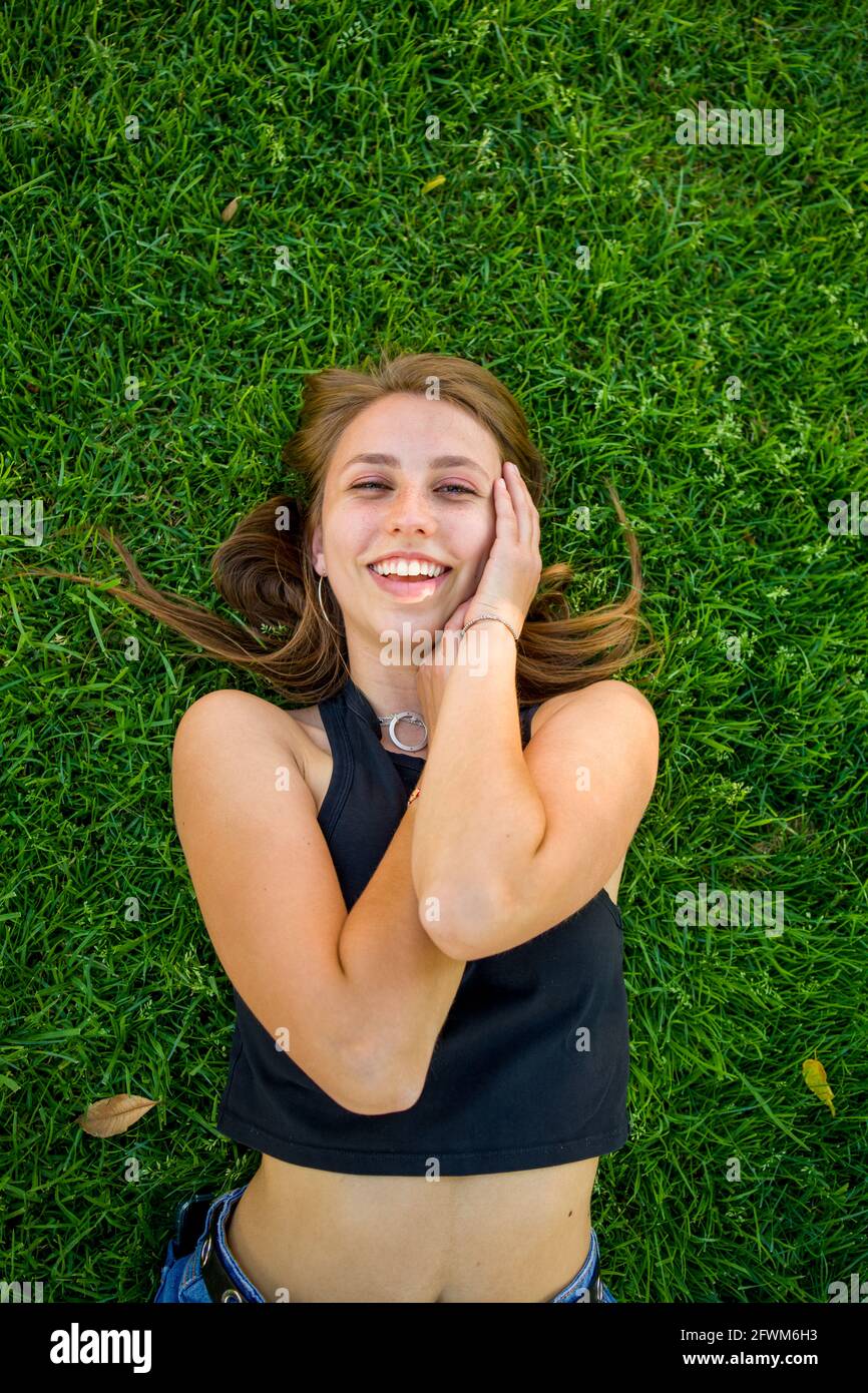 Junge Frau, die auf dem Universitätsgelände auf Gras liegt Stockfoto
