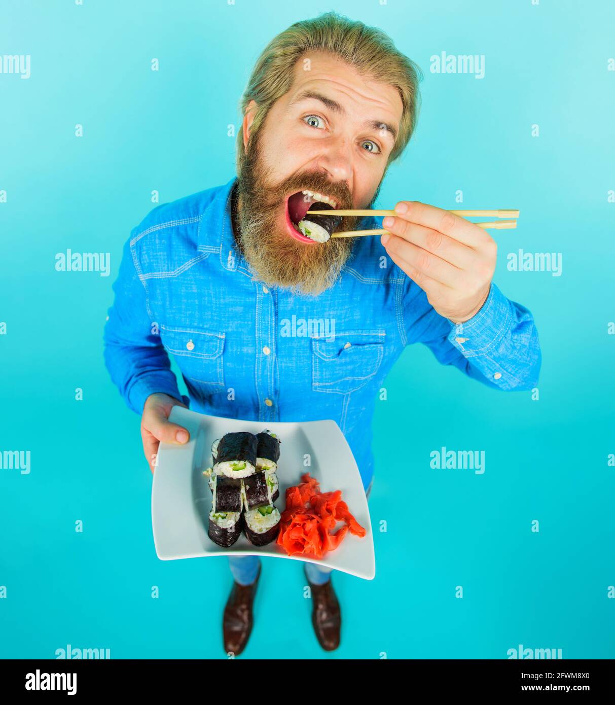 Bärtiger Mann mit einem Teller Sushi-Rolle und eingelegtem Ingwer. Mann, der Sushi isst. Japanisches Essen. Meeresfrüchte. Stockfoto