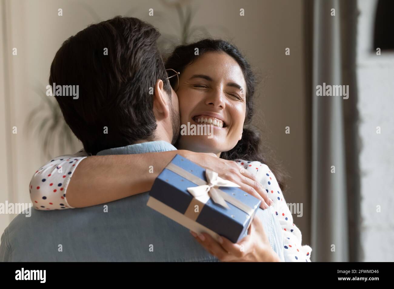 Fröhliche junge Frau kuschelt Mann und fühlt sich dankbar. Stockfoto