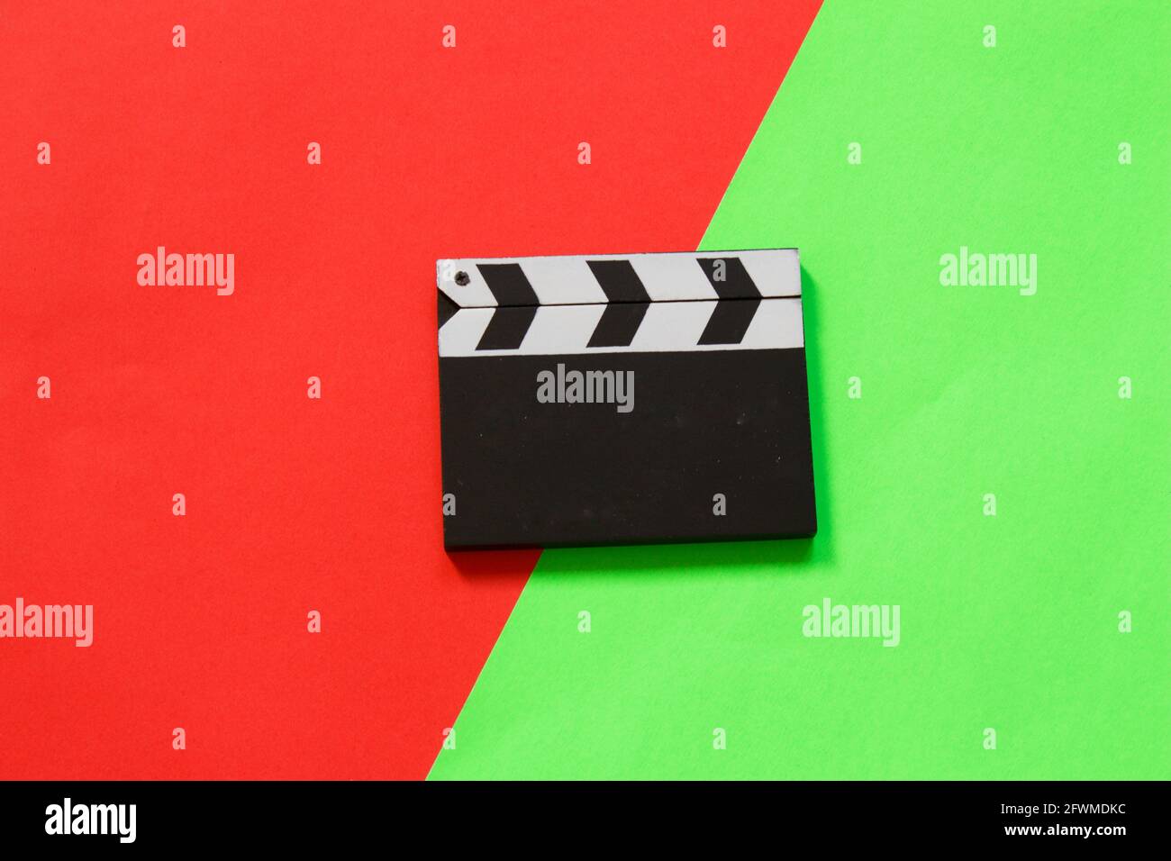 Filmklapper isoliert auf halbrotem halbgrünem Hintergrund. Draufsicht. Unterhaltungsbranche. Platz für Text. Stockfoto