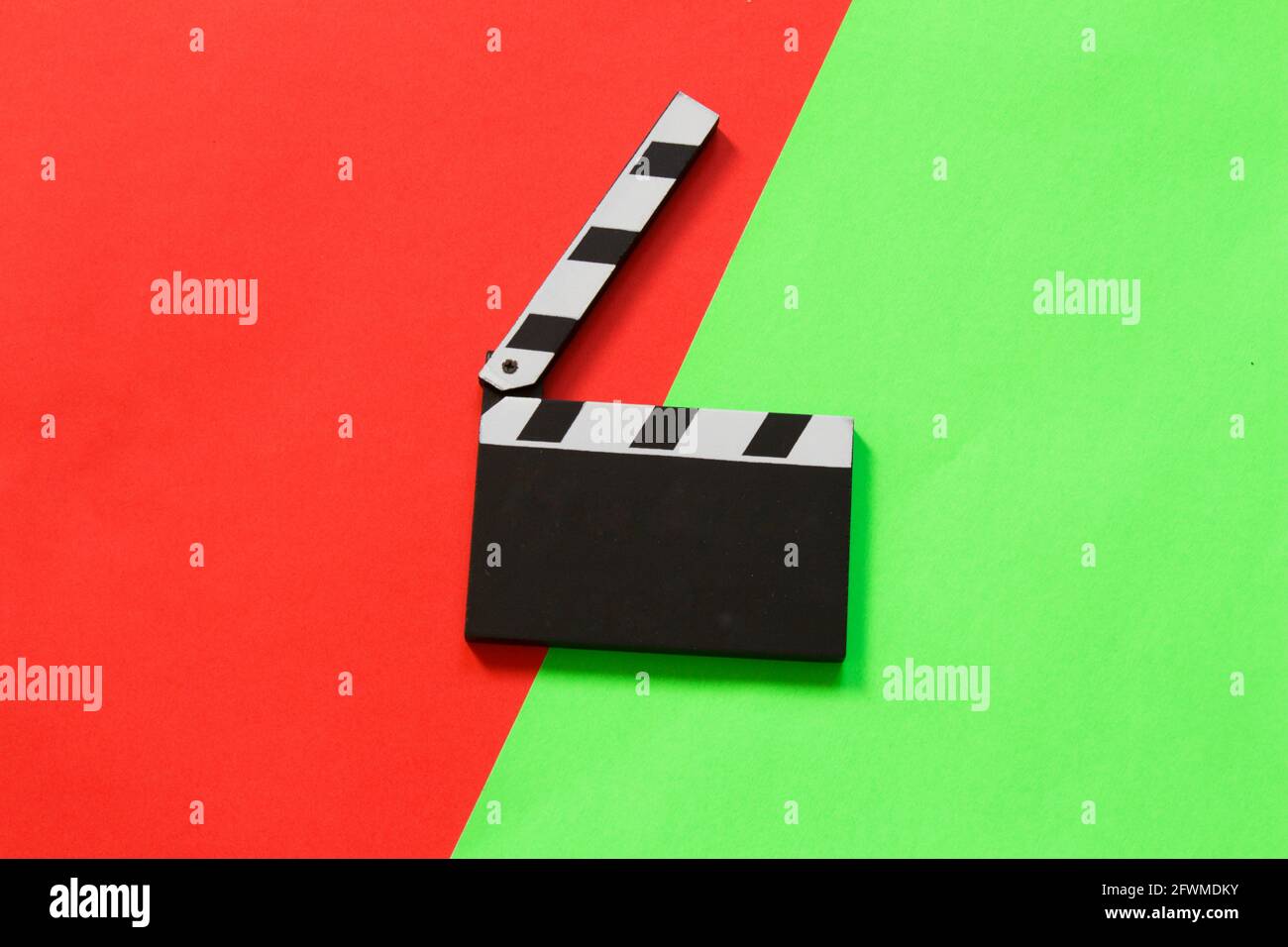 Filmklapper isoliert auf halbrotem halbgrünem Hintergrund. Draufsicht. Unterhaltungsbranche. Platz für Text. Stockfoto