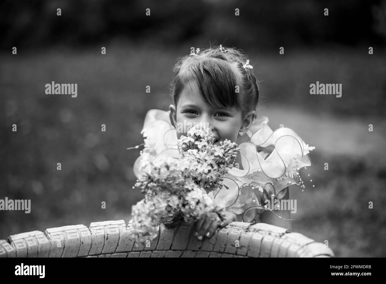 Porträt eines kleinen niedlichen Mädchen sitzt auf einem Park. Schwarzweiß-Foto. Stockfoto