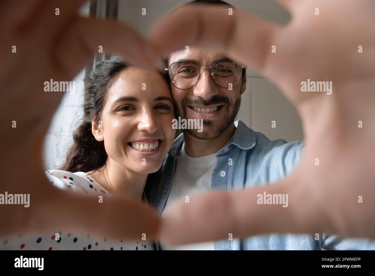 Liebevolles junges verheiratetes Paar, das ein Liebessymbol zeigt. Stockfoto