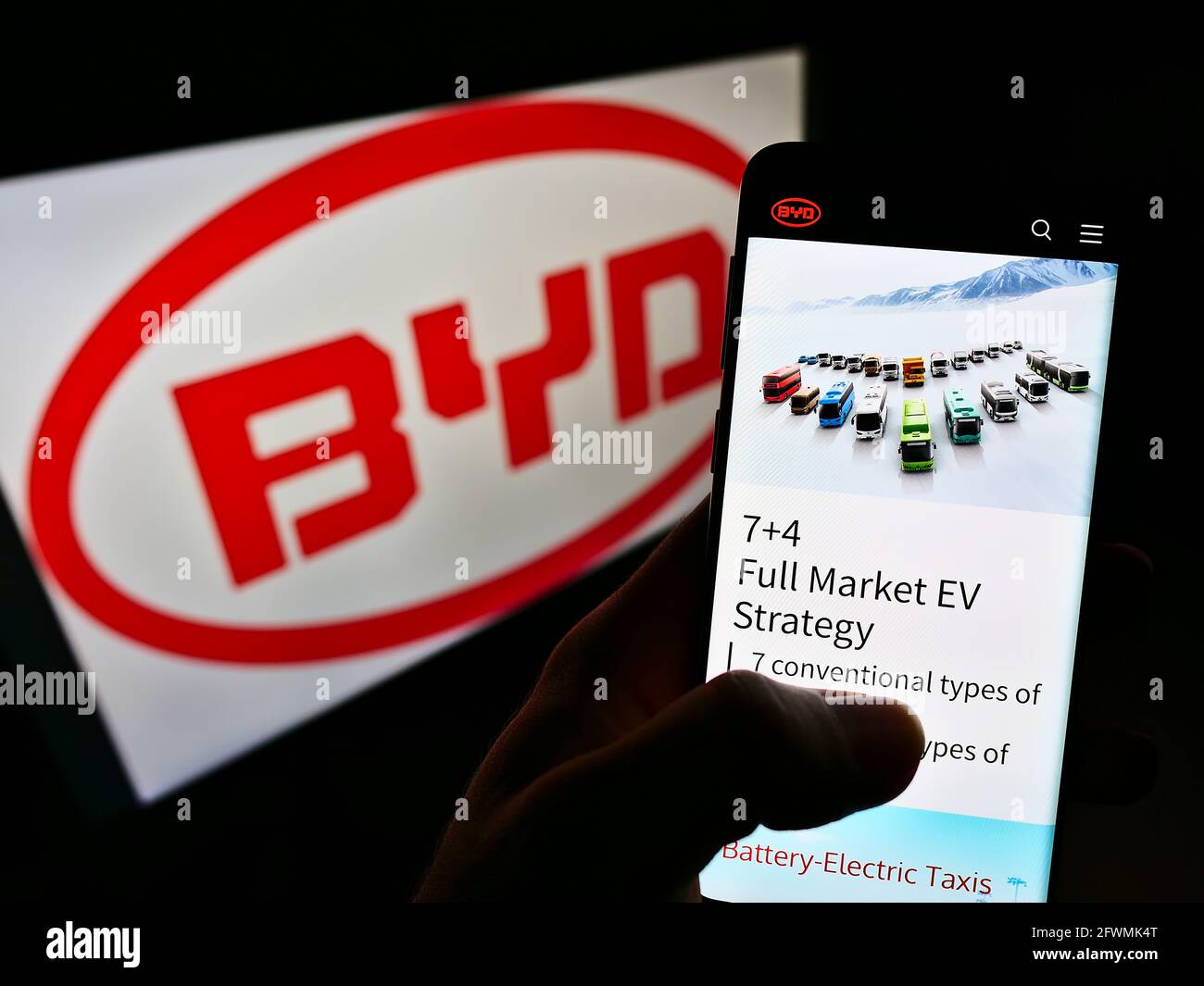 Person, die Mobiltelefon mit der Website des chinesischen Automobilherstellers BYD Co. Ltd. Auf dem Bildschirm vor dem Logo hält. Konzentrieren Sie sich auf die Mitte des Telefondisplays. Stockfoto