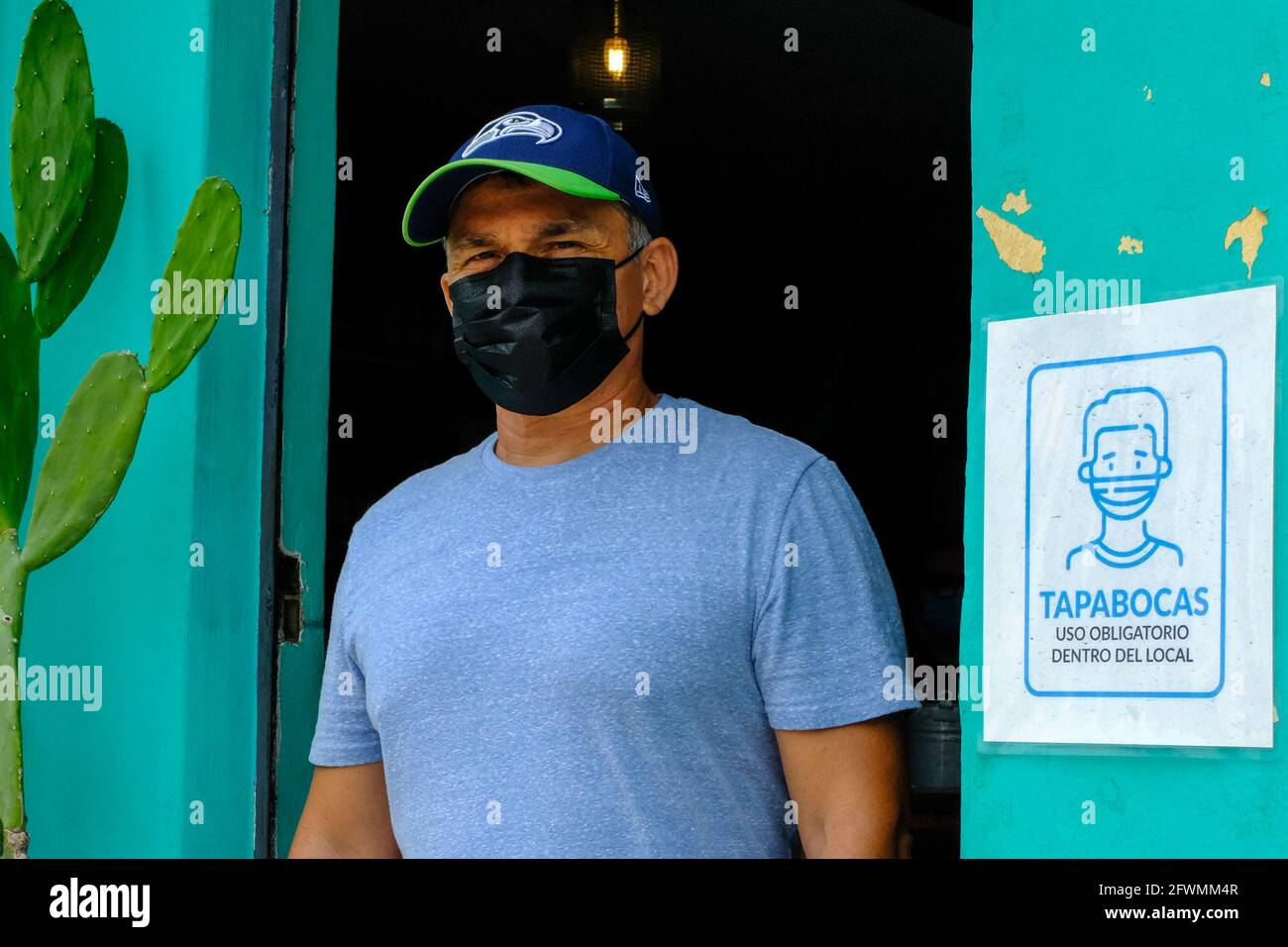 Mann mit Maske und öffentlicher Bekanntmachung, die Menschen dazu anweist, beim Betreten des Establishments, Merida Mexico, eine Maske zu tragen Stockfoto