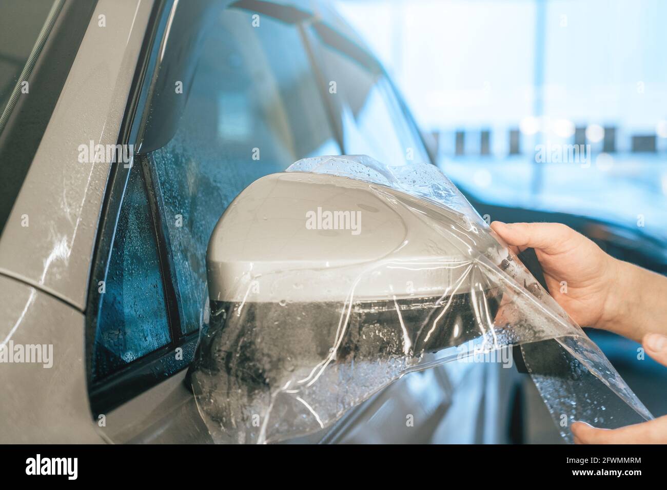 Installation einer PPF- oder Lackschutzfolie oder einer Anti-Kies-Schutzbeschichtung auf dem Autospiegel. Fahrzeugdetails. Stockfoto