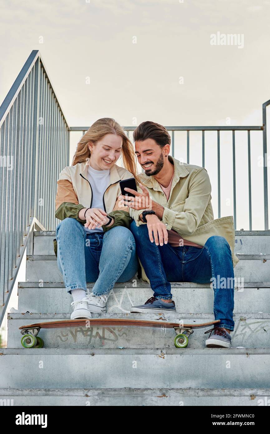 Junge multirassische Paar lächelt, während sie auf ein schauen Telefon Stockfoto