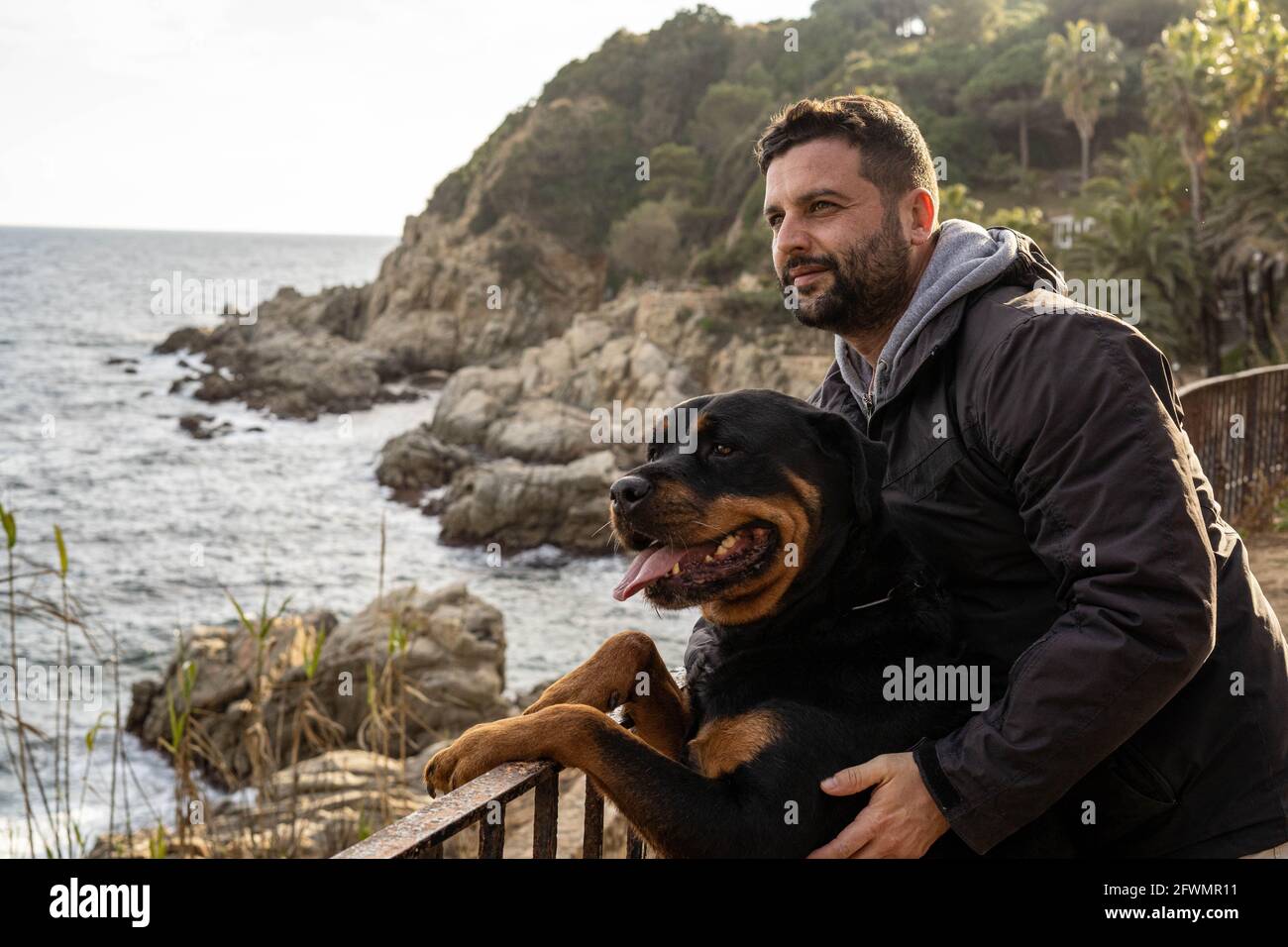 Mann, der mit seinem rottweiler Hund den Meerblick genießt Stockfoto