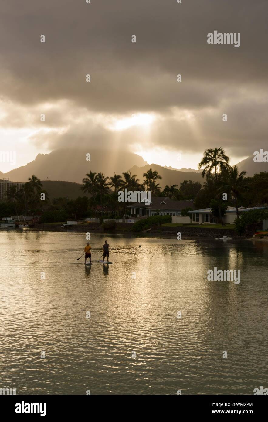 Zwei Männer paddeln an Bord der Kailua Bay bei Sonnenuntergang mit dramatischen Wolken am Himmel. Stockfoto