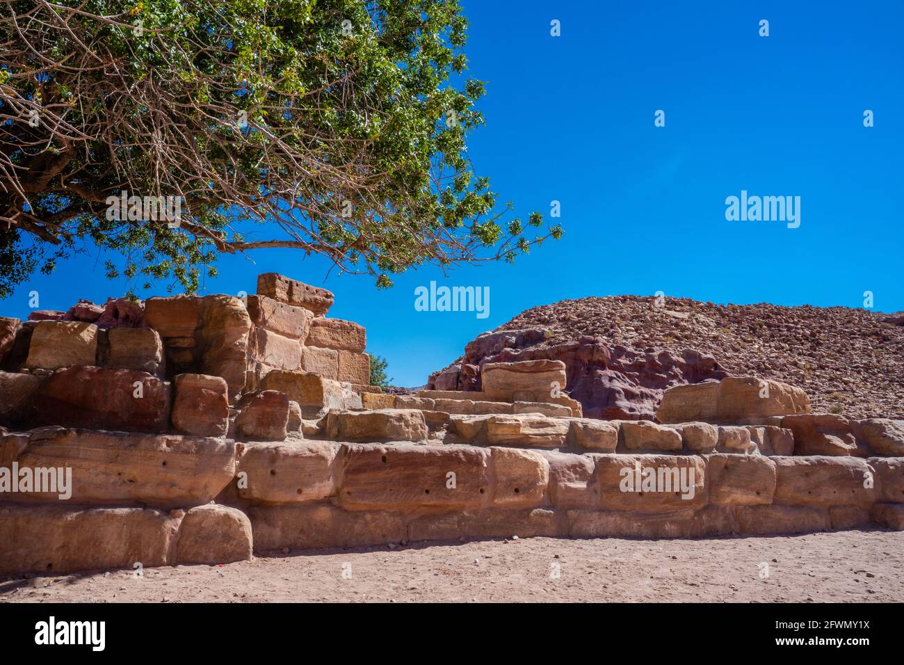 Nahaufnahme der Ruinen von Nymphaeum, halbkreisförmiger öffentlicher Brunnen, der den Wassernymphen gewidmet ist, um 100 n. Chr., unter einem Baum, klarer sonniger Tag, Petra, J Stockfoto