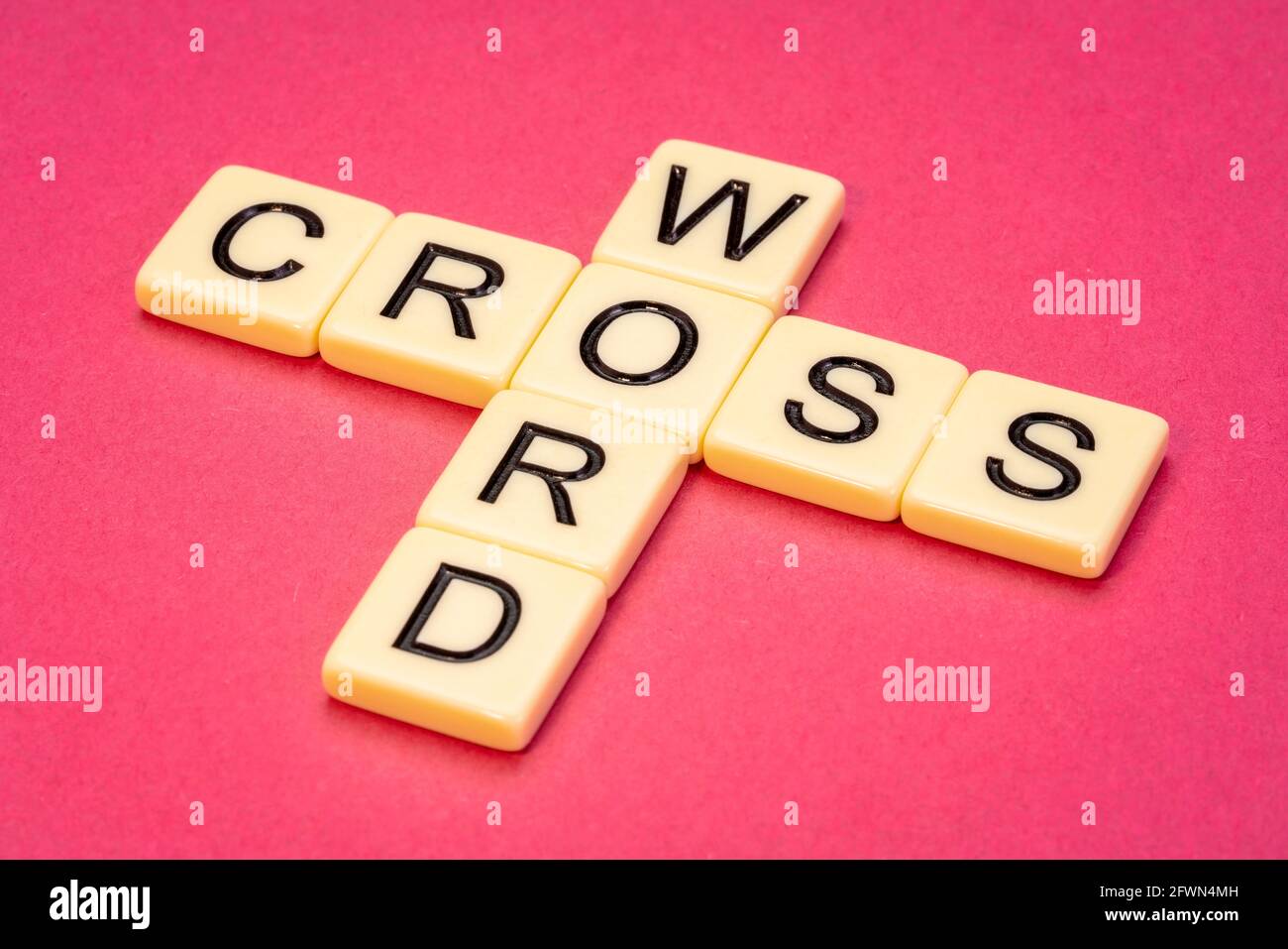 Kreuzworträtsel abstrakt in Elfenbein Buchstaben Fliesen gegen rosa strukturiert handgefertigt Papier Stockfoto