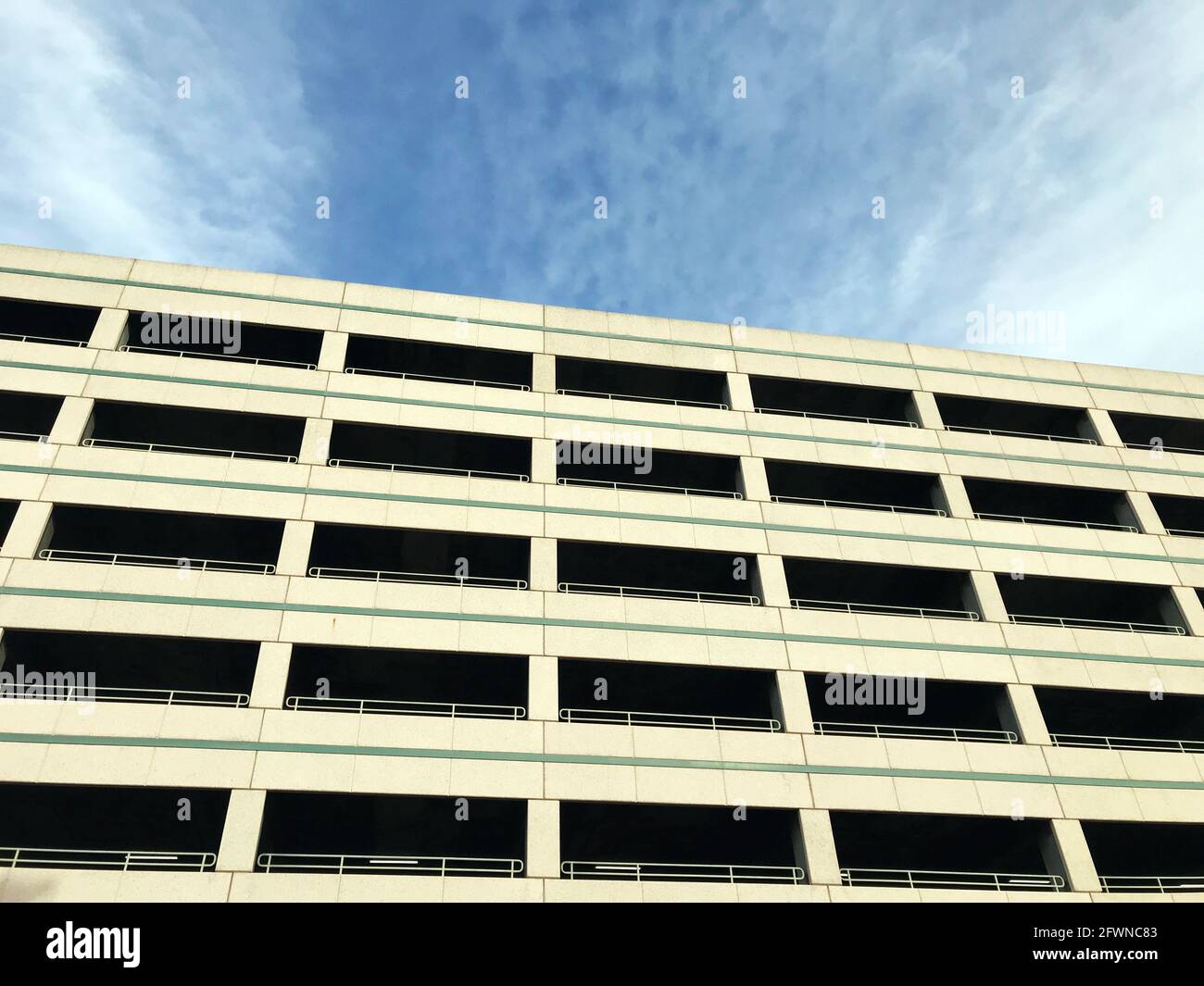 Blick auf die typische mehrstufige Parkgaragenfassade und das Äußere unter blauem Himmel. Stockfoto