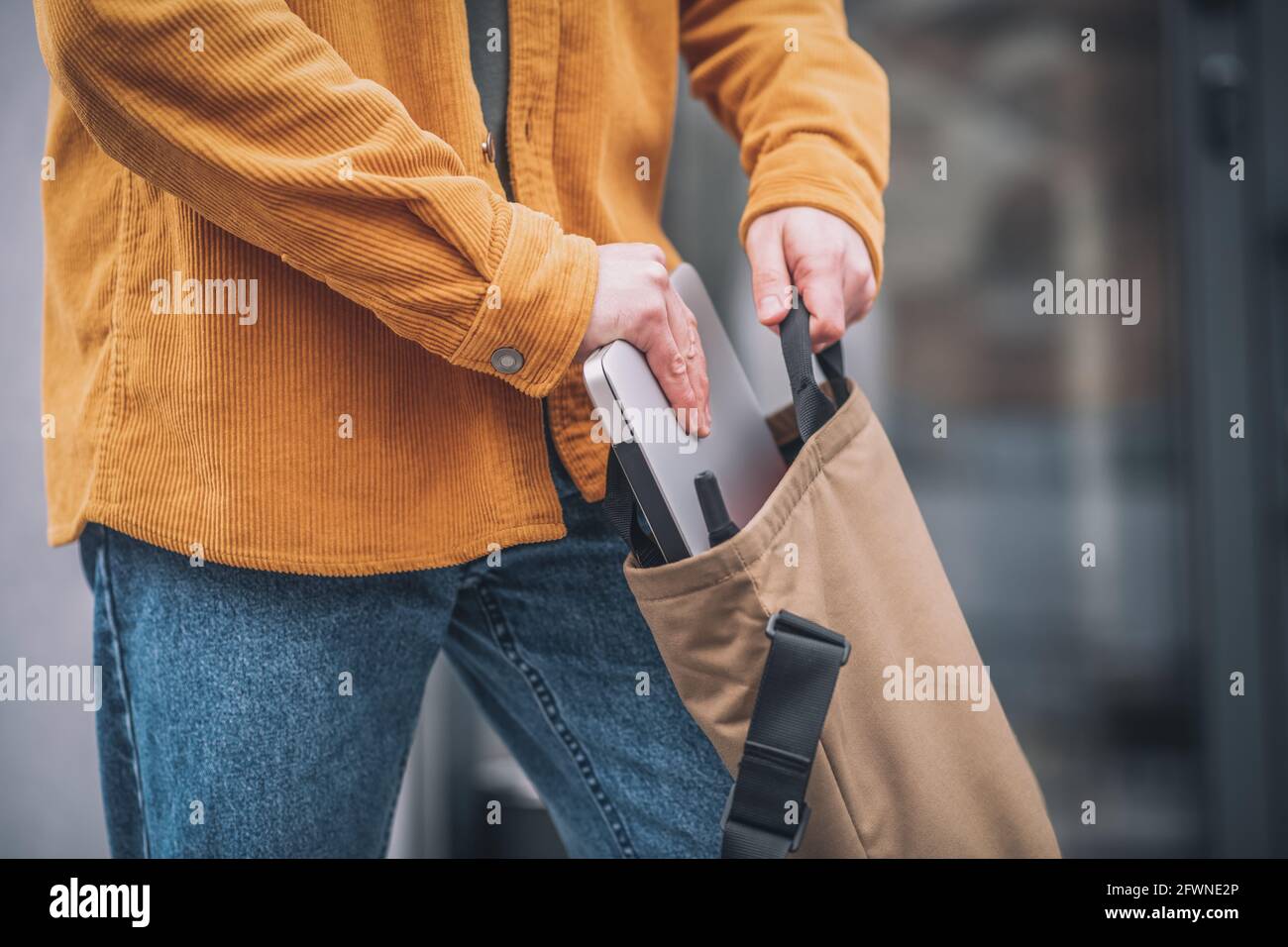 Nahaufnahme der Mans-Hand, die den Laptop in eine Tasche steckt Stockfoto