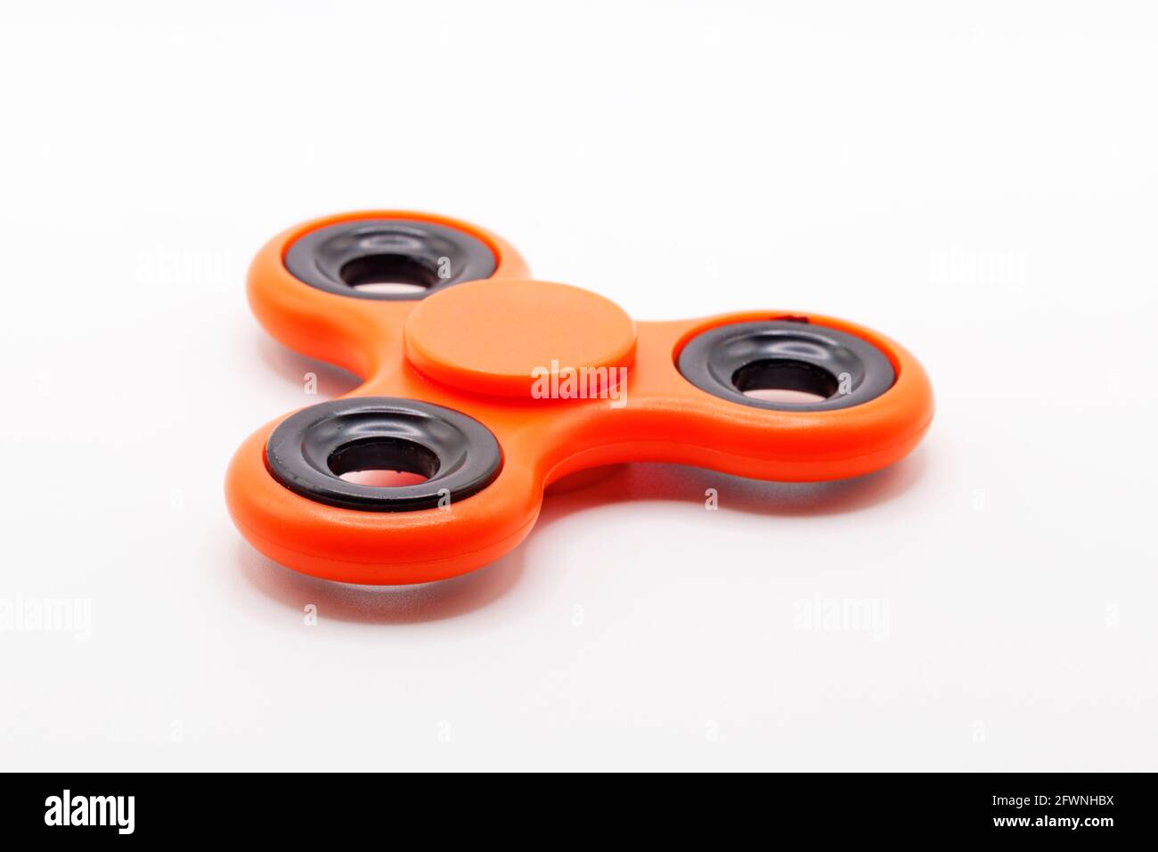 Orangefarbener Fidget-Spinner auf weißem Hintergrund Stockfoto