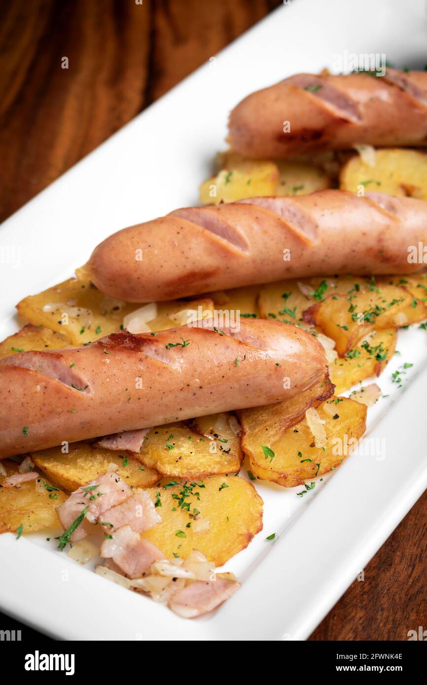 deutsche Bio-Käse- und Schweinefleischwürste mit gebratener Kartoffel und Senf auf Holzhintergrund Stockfoto