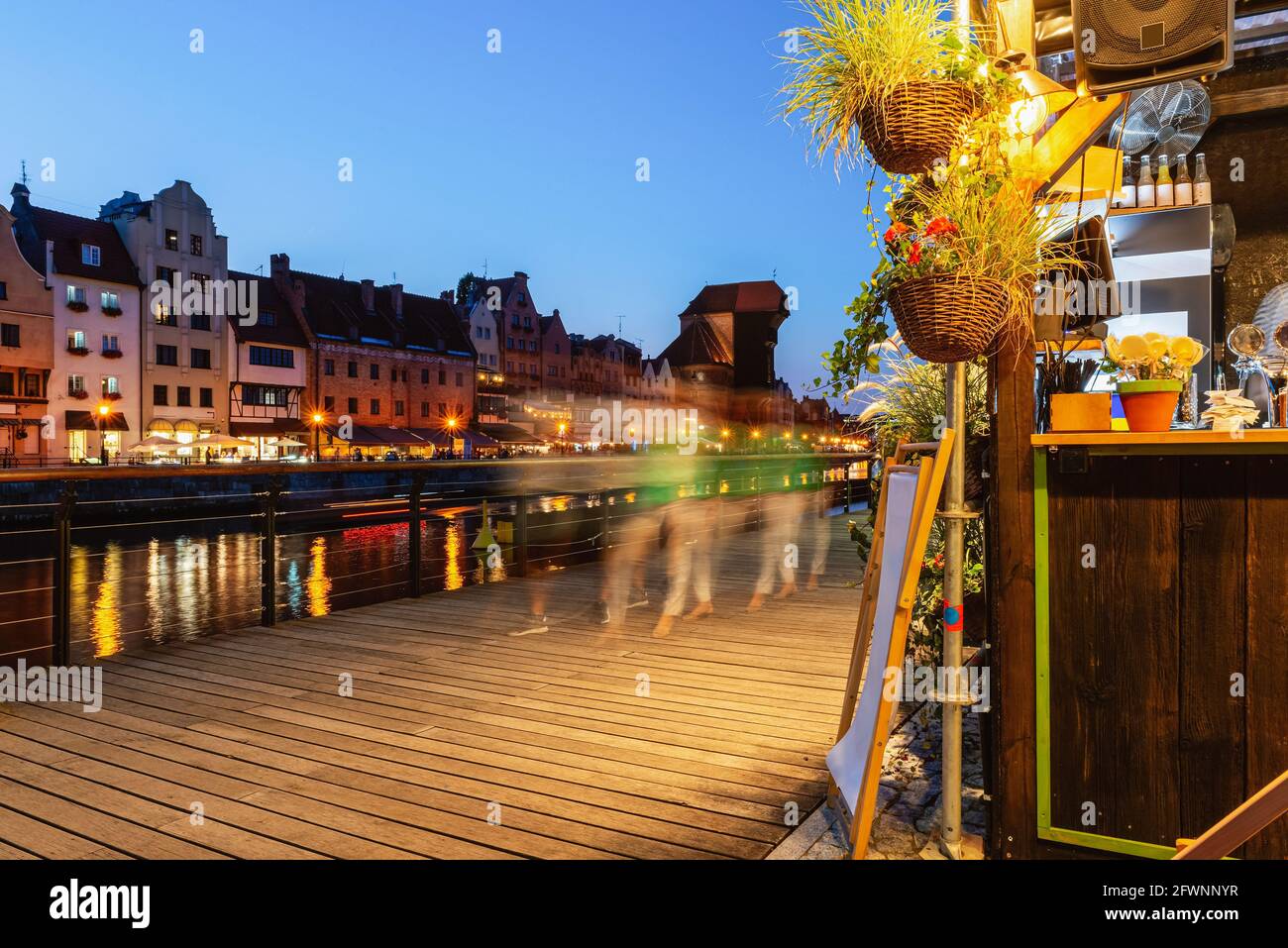 Blick auf die Stadt Danzig bei Nacht, hölzerne Böschung und Straßencafé darauf. Fassaden alter mittelalterlicher Häuser an der Promenade in der Stadt Danzig. Polen. Stockfoto