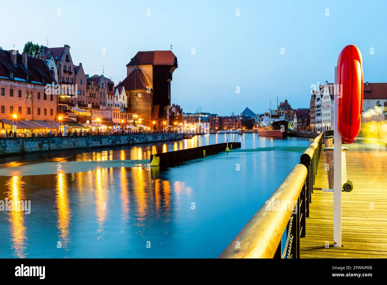 Blick auf die Stadt Danzig bei Nacht am Fluss. Blick auf den berühmten Kran und die Fassaden der alten mittelalterlichen Häuser an der Promenade in Danzig Stadt. Polen. Stockfoto