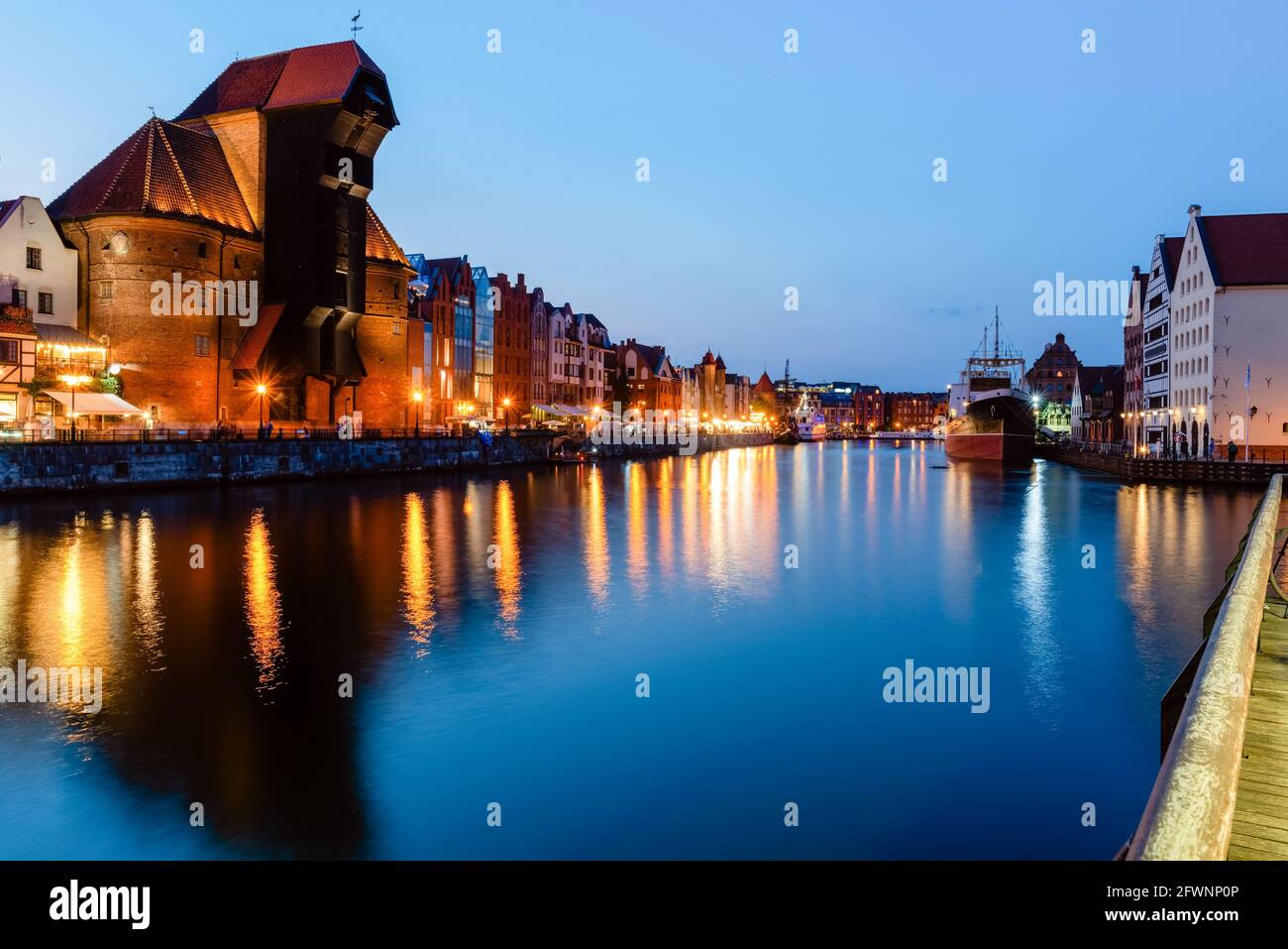 Blick auf die Stadt Danzig bei Nacht am Fluss. Blick auf den berühmten Kran und die Fassaden der alten mittelalterlichen Häuser an der Promenade in Danzig Stadt. Polen. Stockfoto